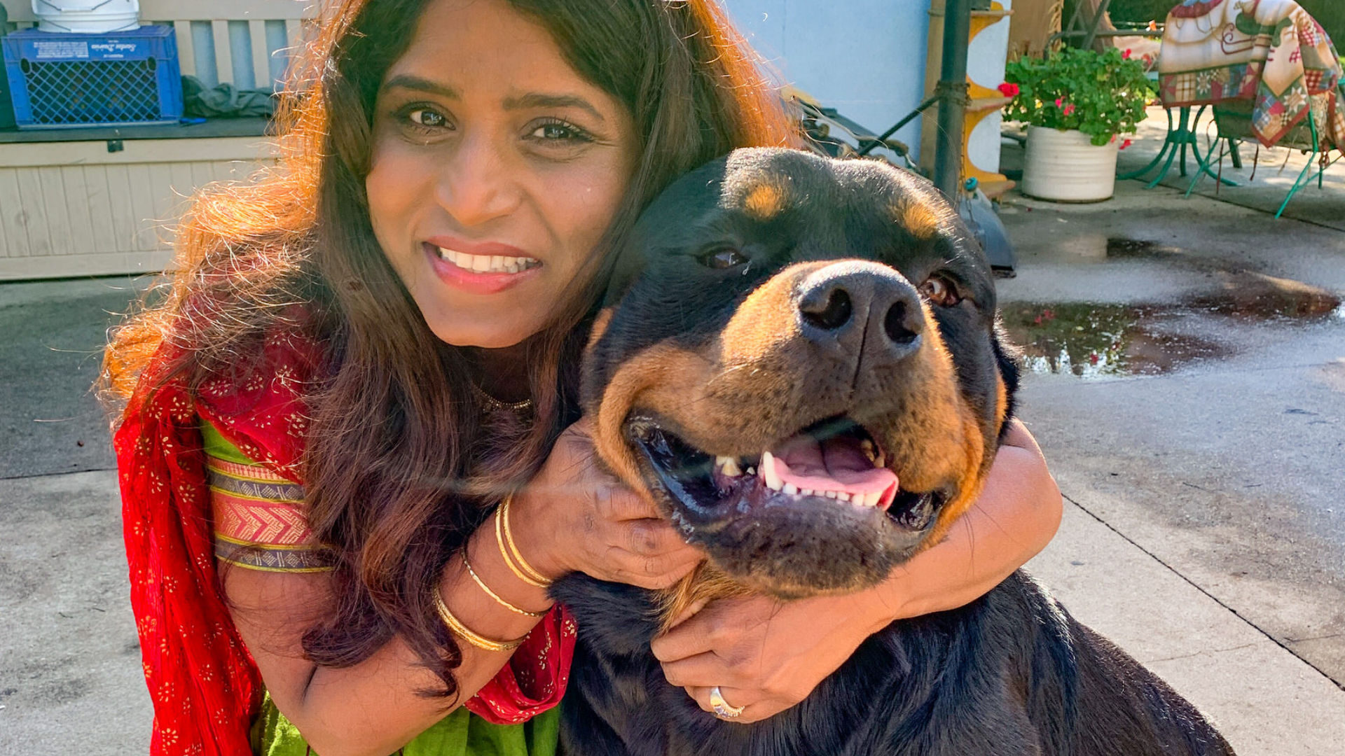 Woman hugging a Rottweiler dog outdoors on a sunny day.