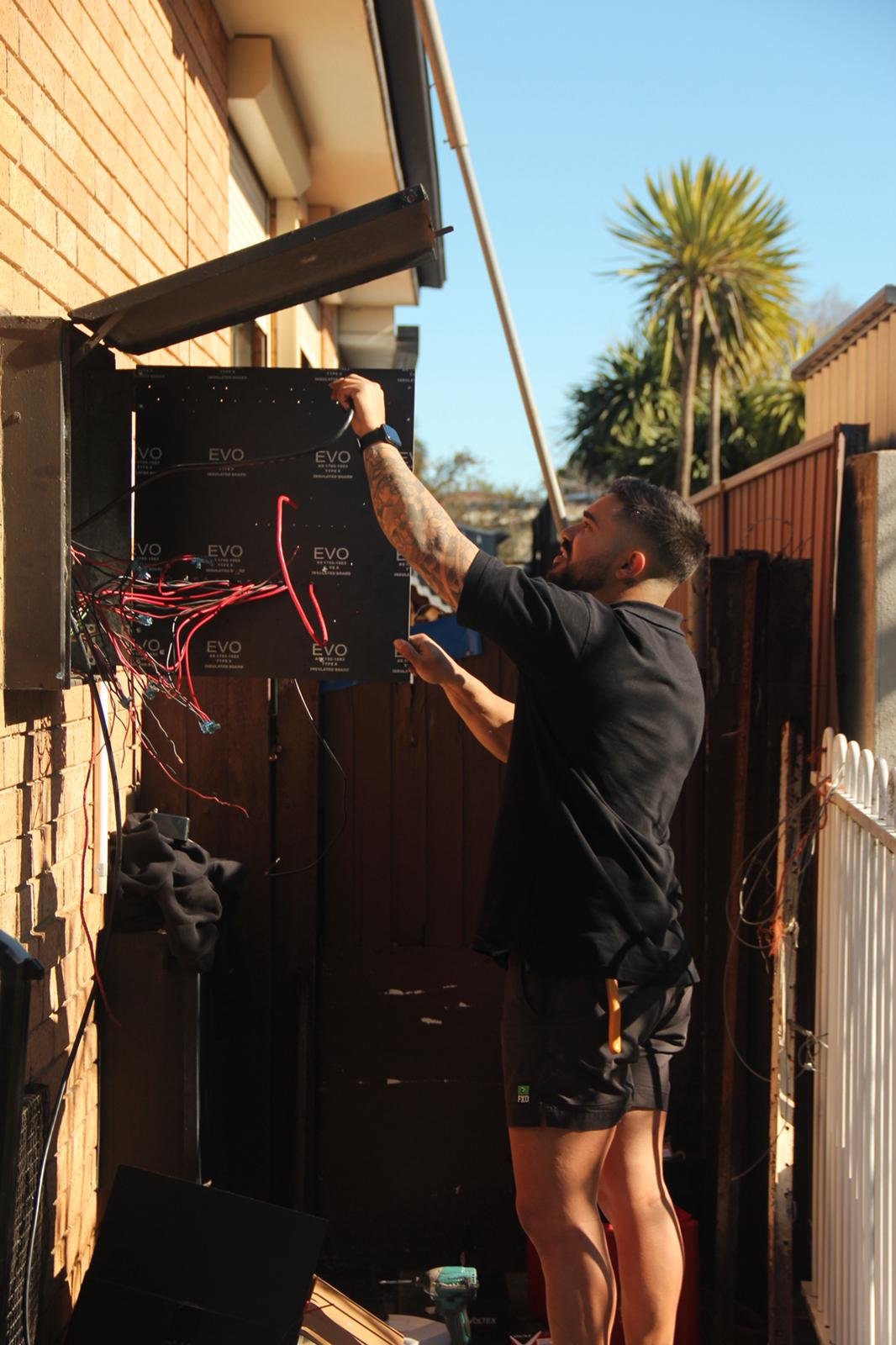 Zamps Electrical technician servicing an outdoor electrical panel at a residential property in sunny weather