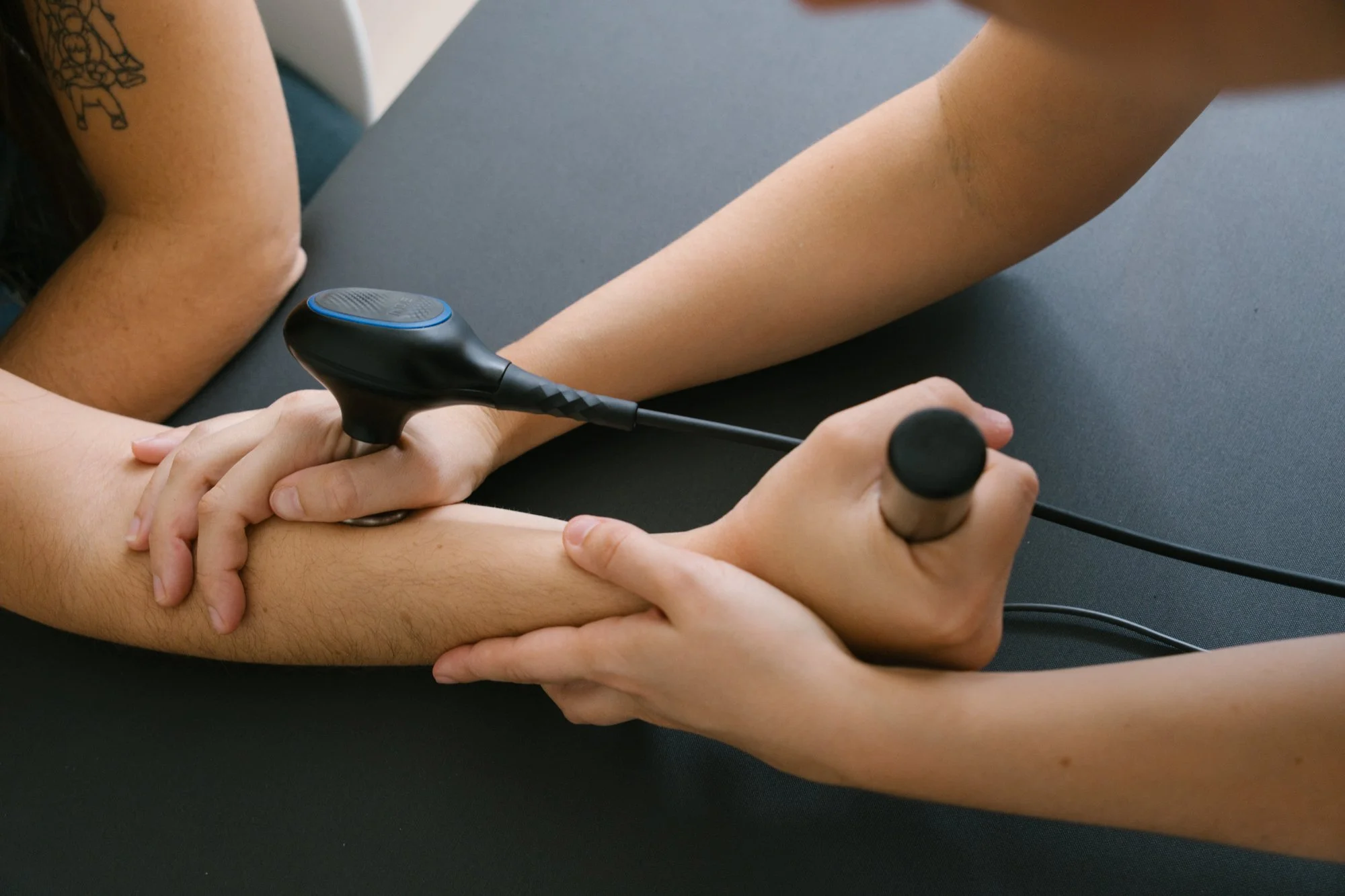 Una persona recibe terapia de movilización o masaje en su brazo por parte de otra persona en un entorno clínico.