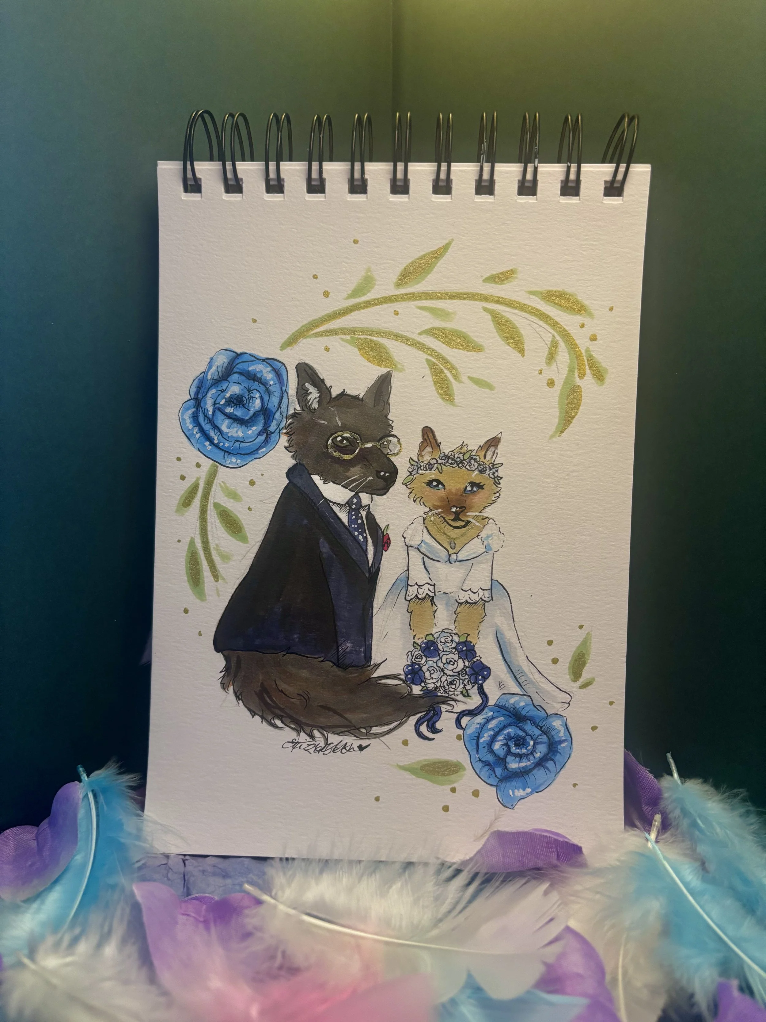 A watercolor painting of two anthropomorphic cats dressed as a bride and groom, surrounded by blue roses and green foliage.