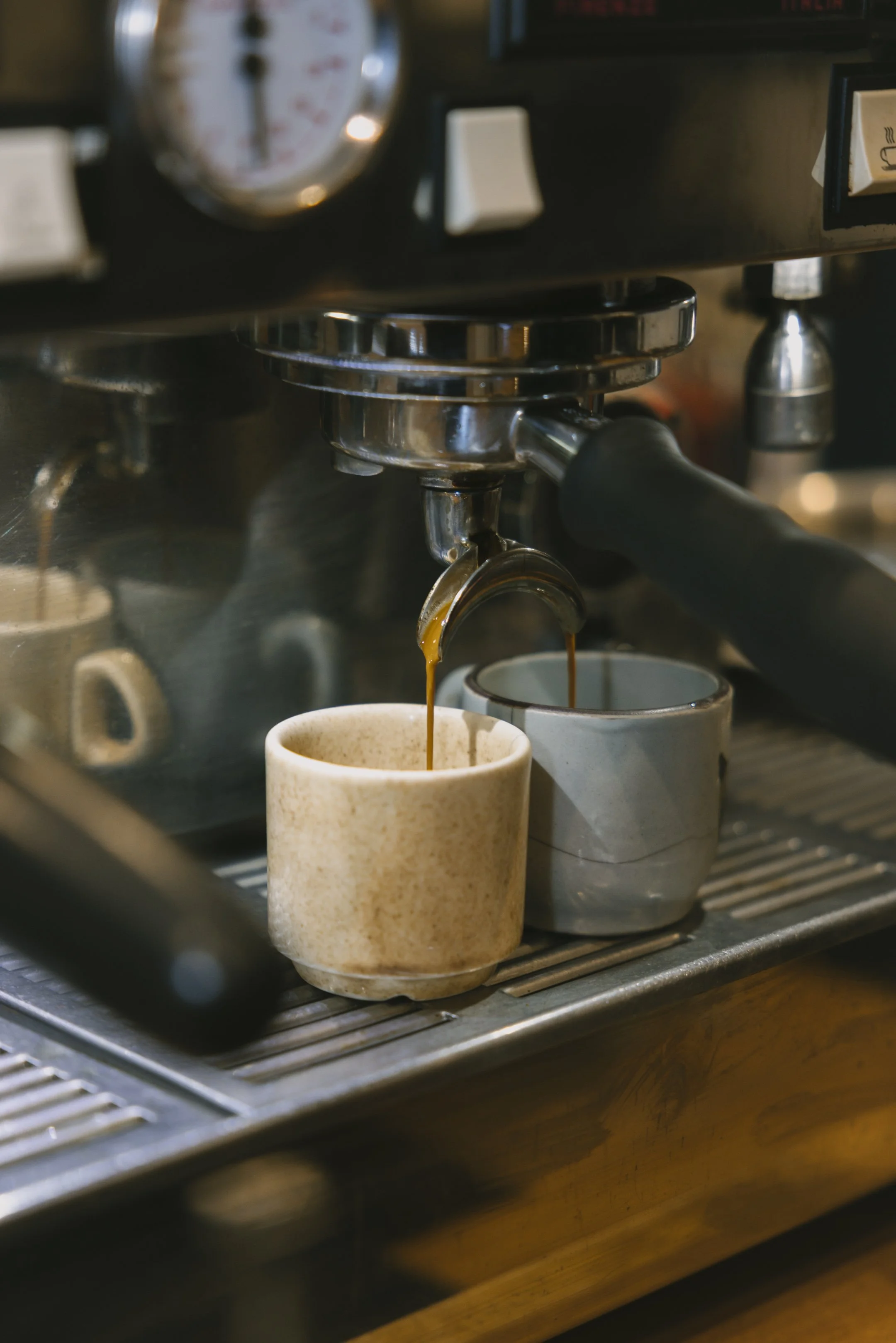 A person holding a watercolor painting of a face with warm tones of orange, pink, and red, surrounded by multiple other watercolor paintings in various colors on paper.