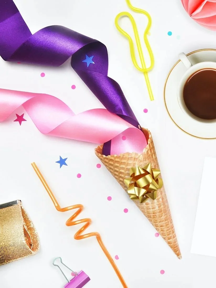 Bunte Partydekoration mit Konfetti, Geburtstagshütchen, Kaffee und Papierclip auf weißem Hintergrund.