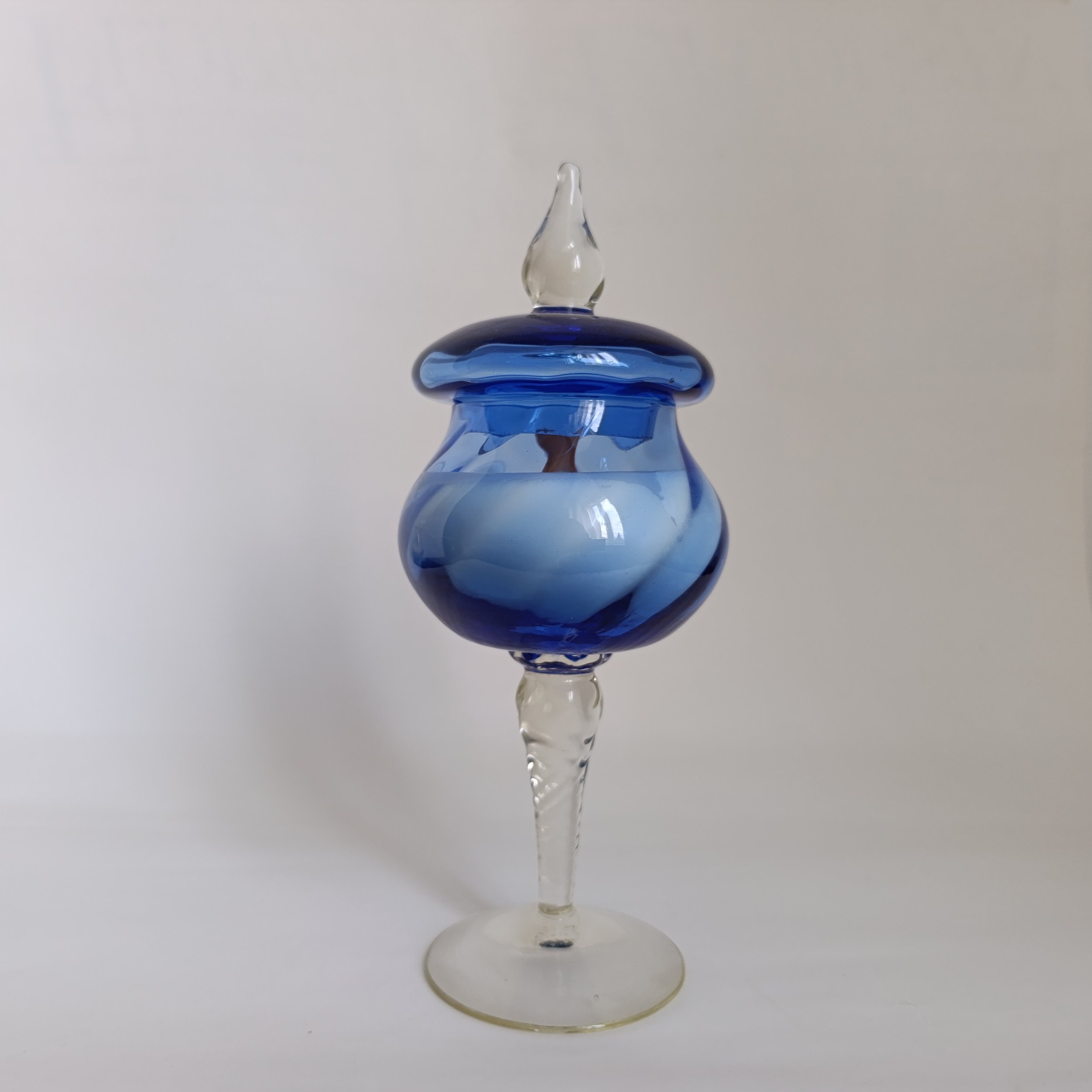 Vase en verre soufflé de couleur bleue avec une base transparente, forme arrondie et haut pointu, sur fond blanc.