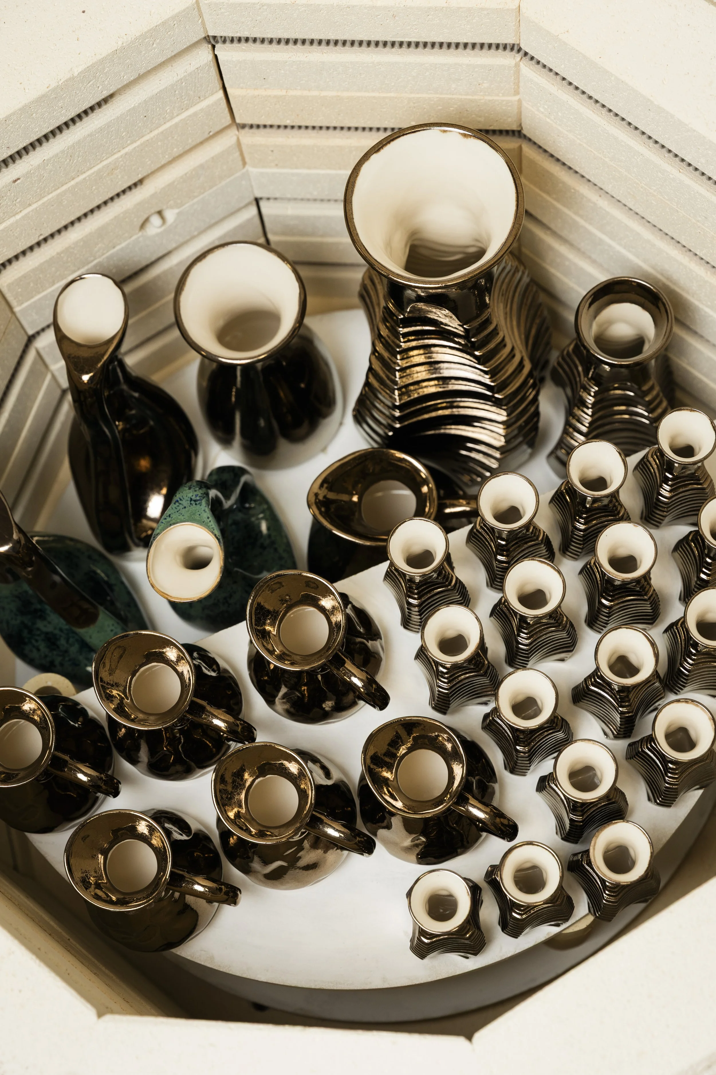 A ceramic kiln with the lid open, showing multiple glaze-fired pieces by Scottish ceramicist, Arra Fletcher.