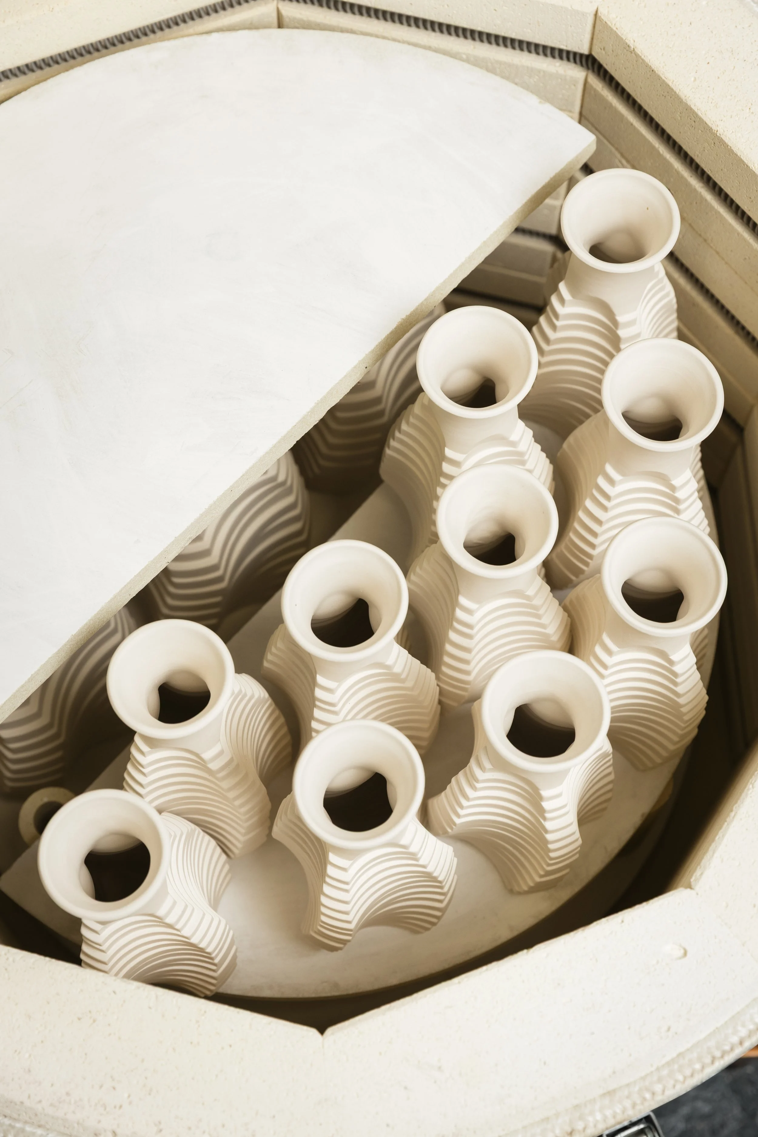 A ceramic kiln with the lid open, showing multiple bisque-fired pieces by Scottish ceramicist, Arra Fletcher.