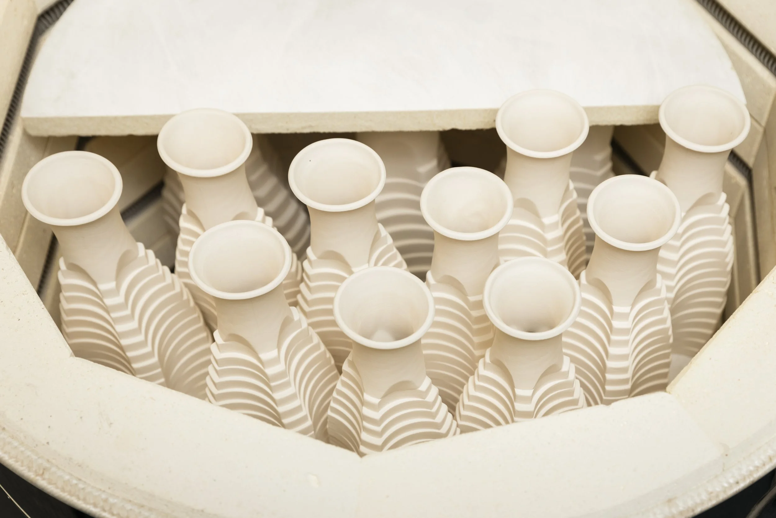 A ceramic kiln with the lid open, showing multiple bisque-fired pieces by Scottish ceramicist, Arra Fletcher.