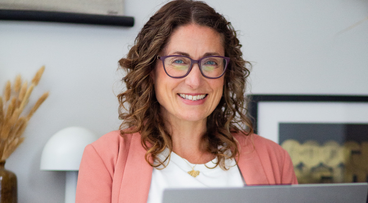 Photo of smiling lady in front of computer.
