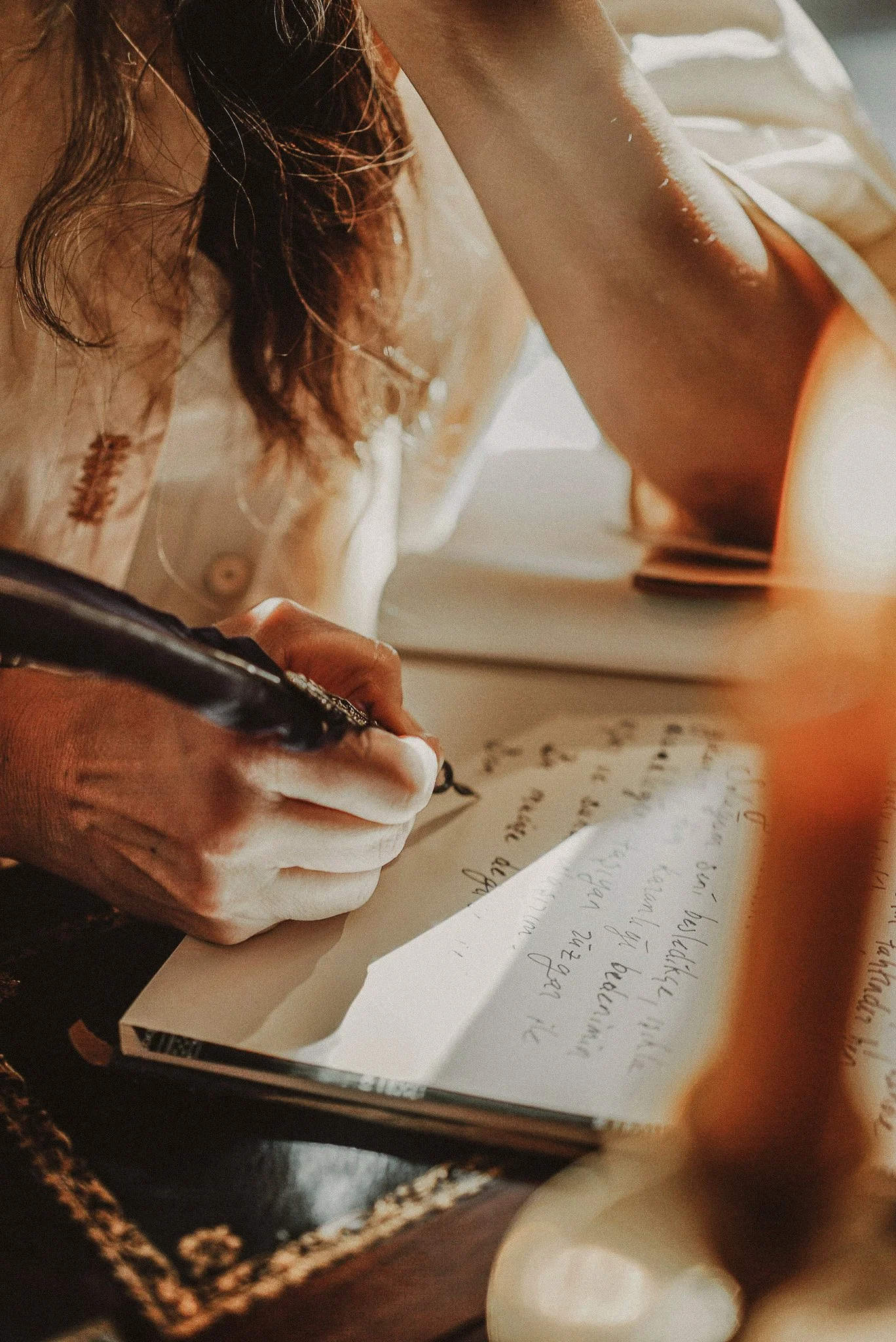 A person with brown hair writing in a notebook with cursive handwriting.
