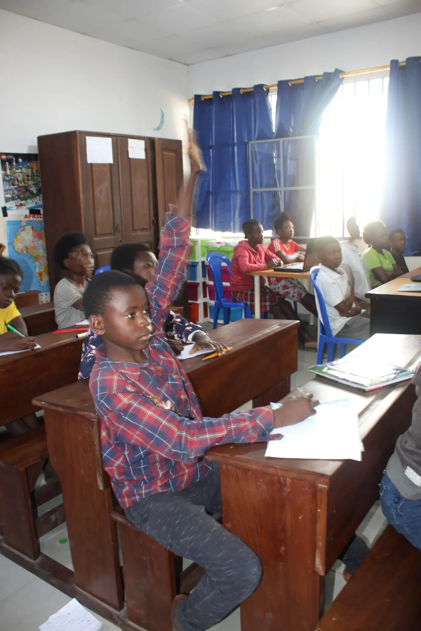 Schüler in einem Klassenzimmer, mit einem Jungen, der die Hand hebt.