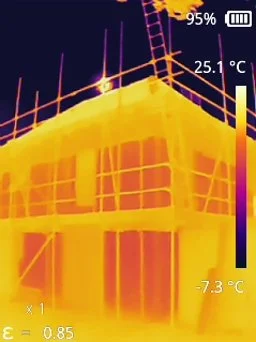 Infrared thermal image of a building under construction, showing heat distribution with warm colors indicating heat and cooler colors indicating less heat.