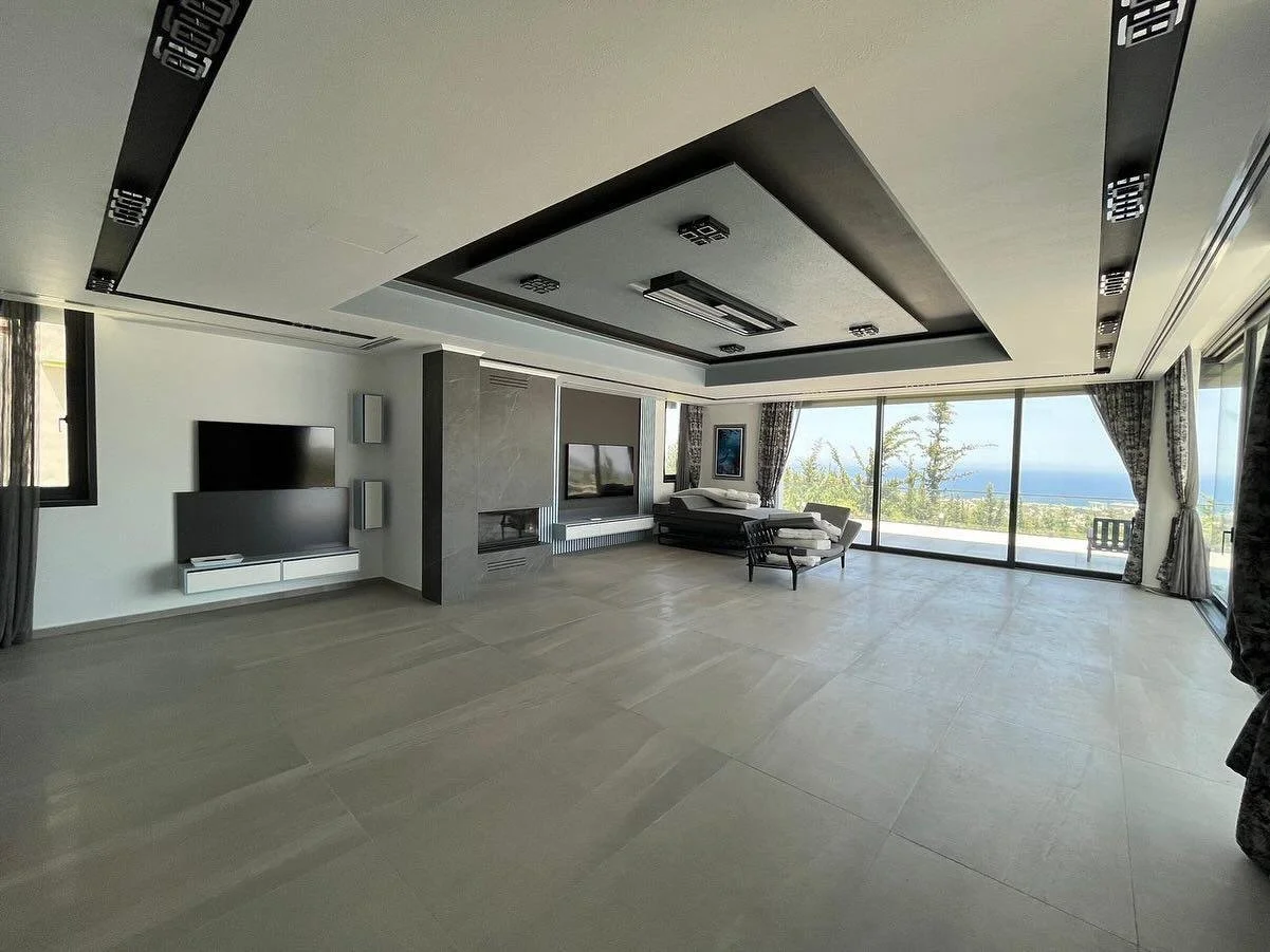 Spacious modern living room with large sliding glass doors revealing ocean view, minimal furniture, and contemporary decor.