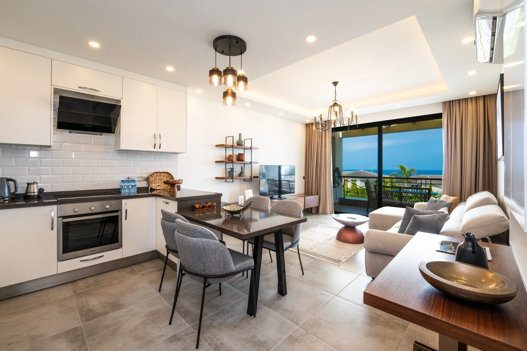 Open-concept living room and kitchen with sliding glass door to balcony and ocean view