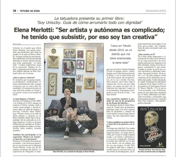 Mujer sentada en un sofá rodeada de cuadros en la pared, en una galería de arte o estudio de tatuajes, con varias obras enmarcadas y una iluminación de exposición artística.