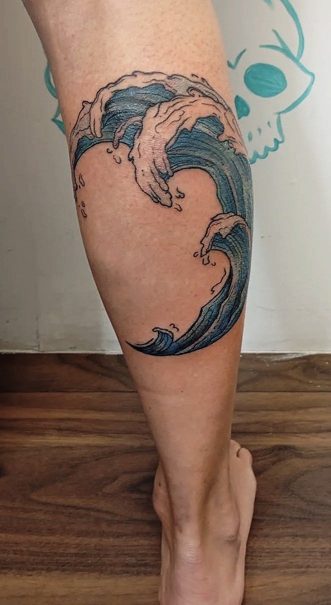 Tatuaje de una ola grande en la parte posterior de la pierna.