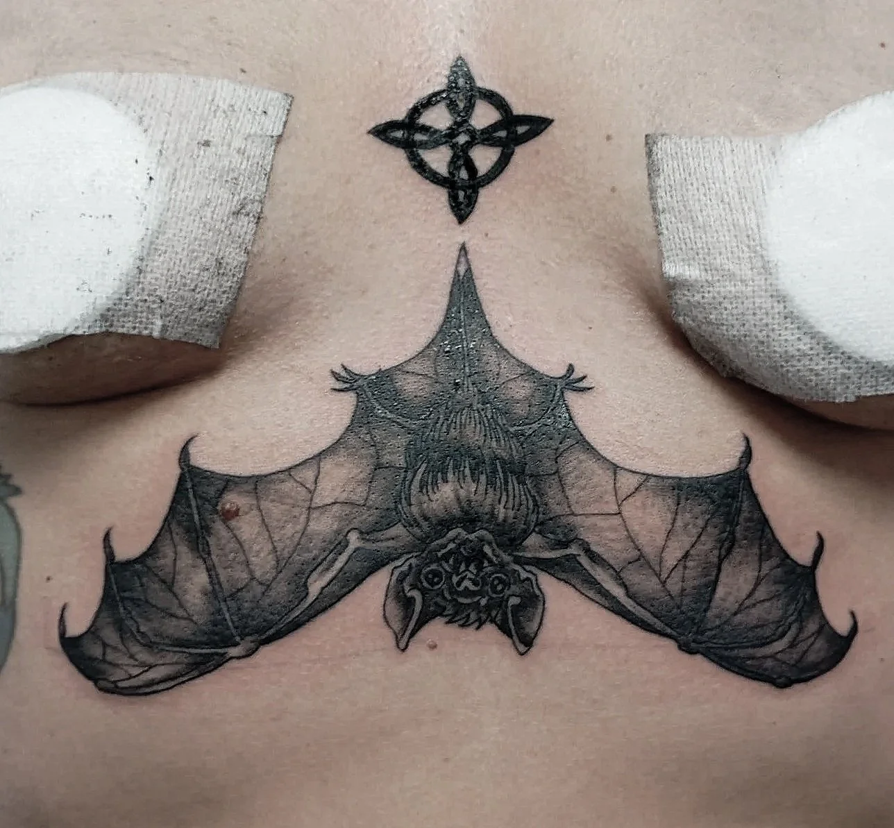 Tatuaje de un murciélago con alas extendidas y una telaraña en su cuerpo, ubicado en el pecho