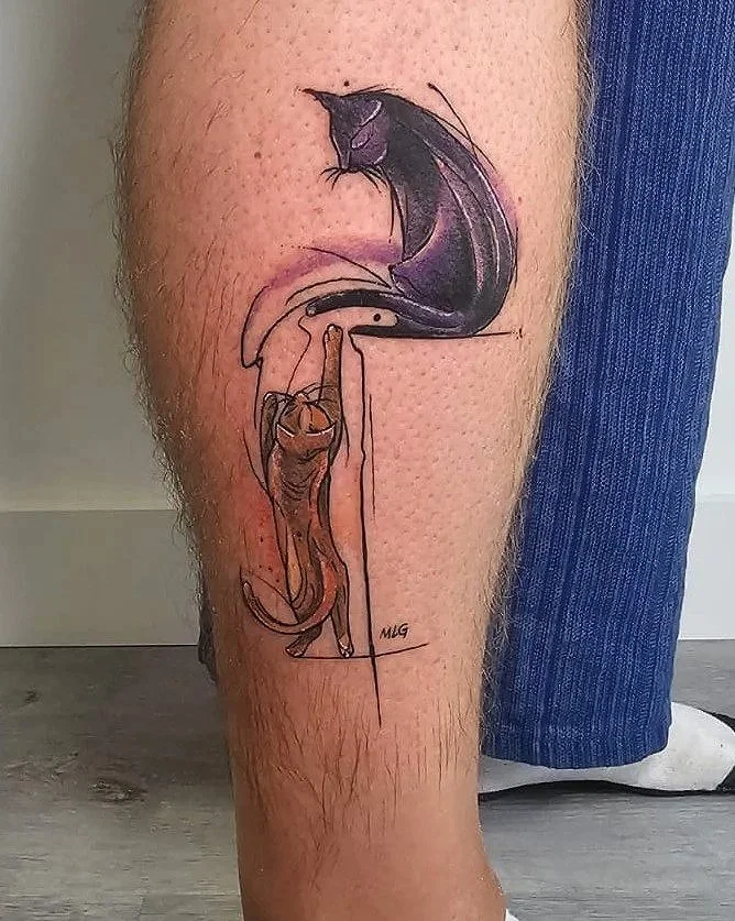 Tatuaje en la pierna que combina un gato en color negro y gris en la parte superior con un dibujo de un gato en tonos naranjas y marrón en la parte inferior, ambos conectados por un diseño artístico.
