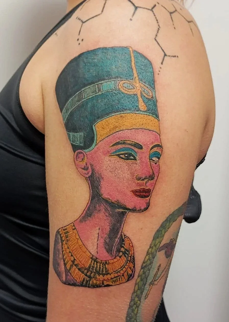 Tatuaje de una mujer egipcia clásica con tocado y collar ornamentado.