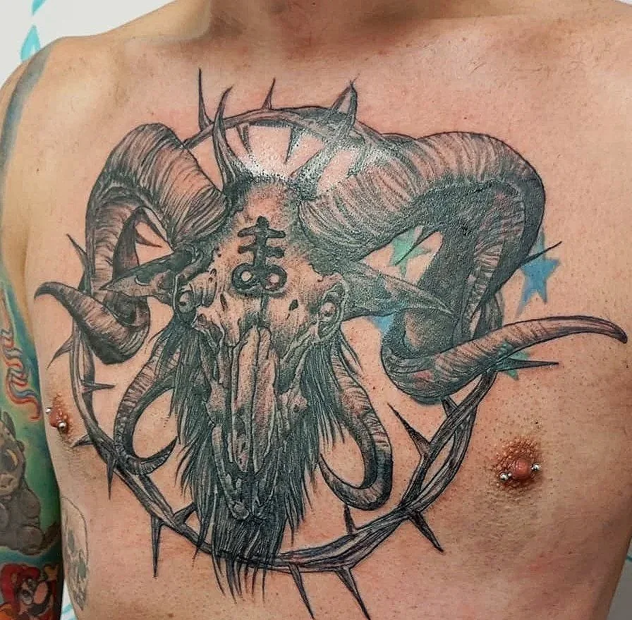 Tatuaje en el pecho de un demonio con cuernos, una calavera, y una corona de espinas.