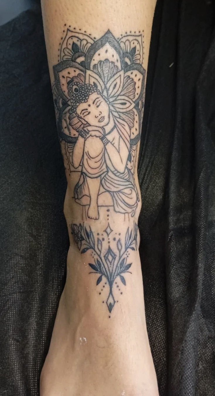 Tatuaje en el brazo de un dibujo de una figura femenina con orejas de mariposa, rodeada de detalles florales y patrones decorativos.