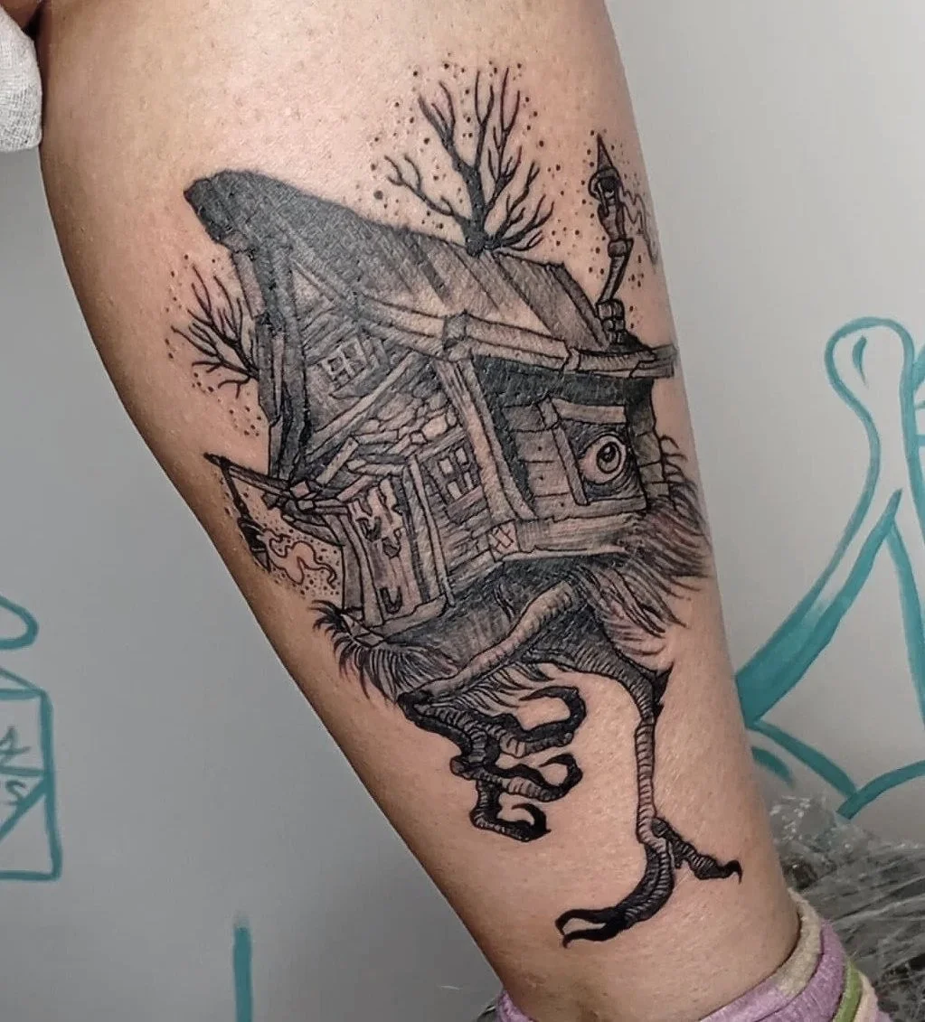 Tatuaje de una casa en forma de ave con árboles y nubes en la espalda.