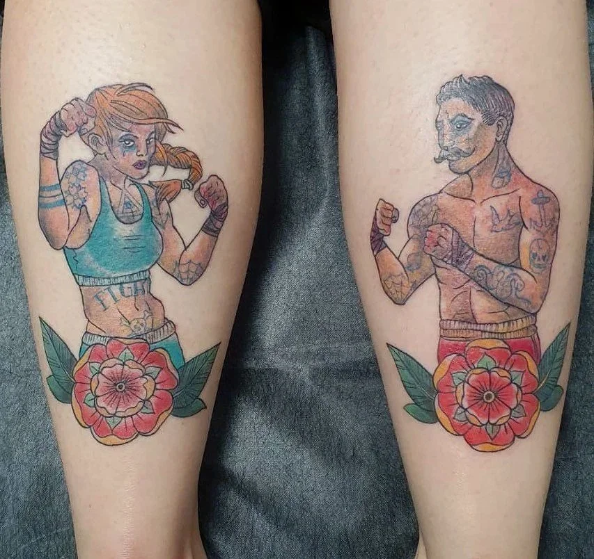 Tatuajes de una mujer levantando el brazo y un hombre con antebrazos cruzados, ambos con flores debajo.