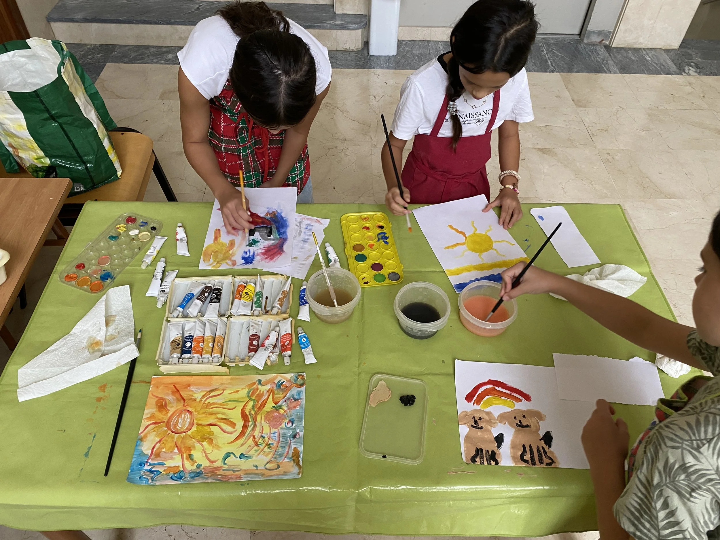 Children painting colorful pictures at a table covered with art supplies at our Sunday school in San Pedro