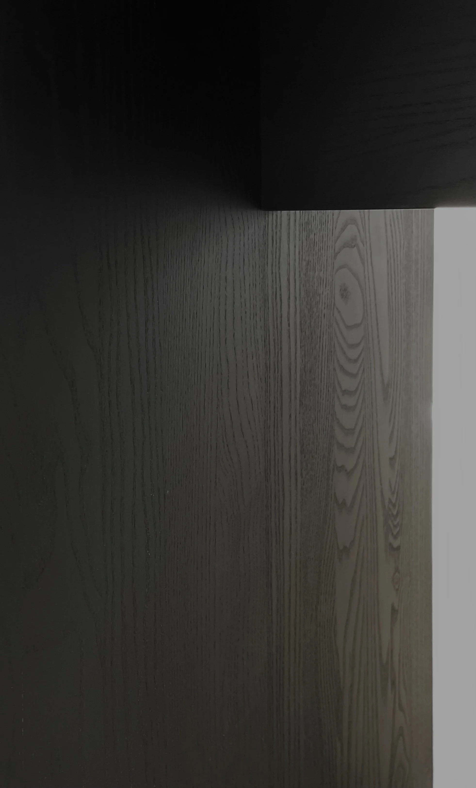 Nahaufnahme einer dunklen Holzoberfläche, Bildkomposition mit geradliniger Formensprache.