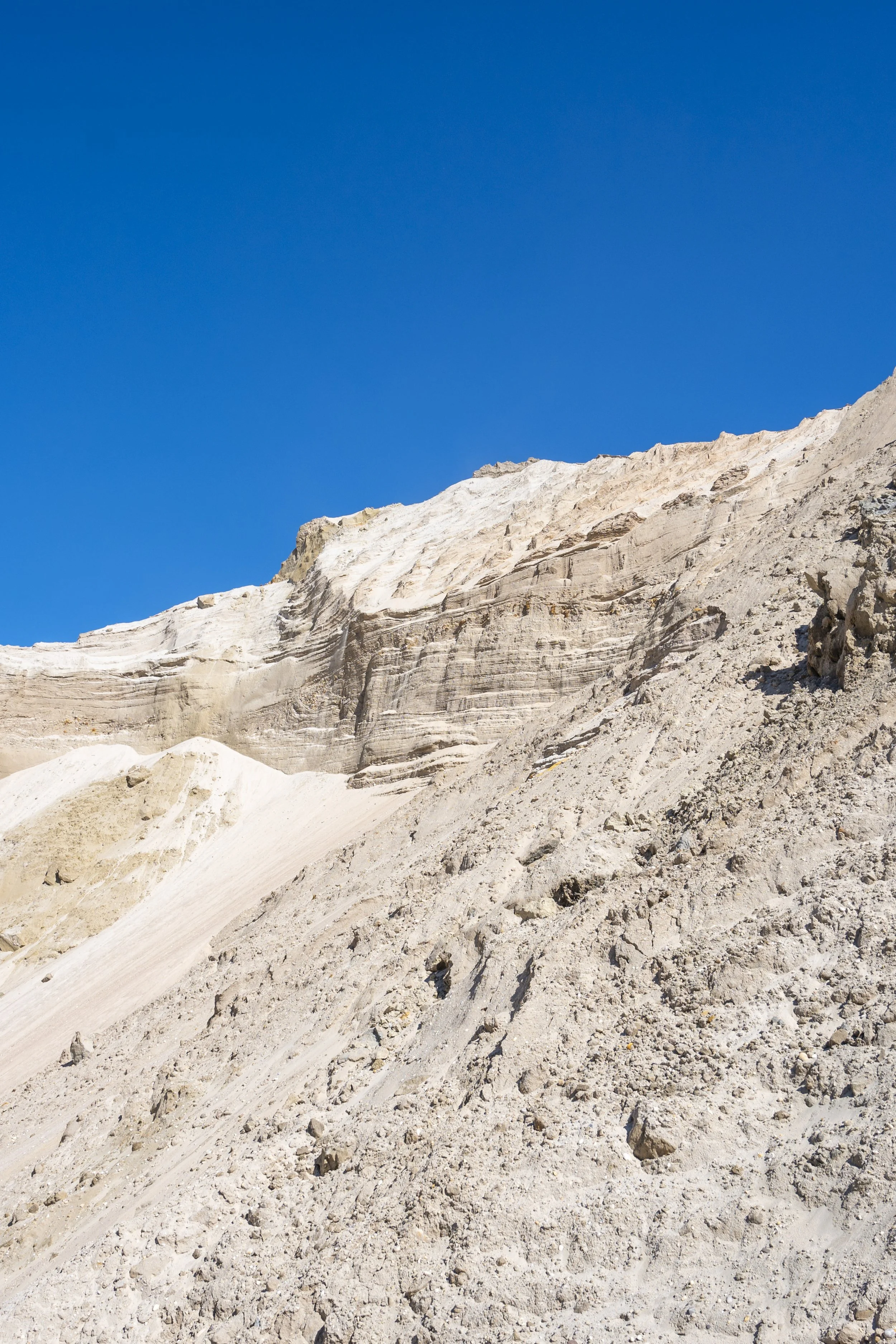 A rugged, sandy mountain slope under a clear blue sky.