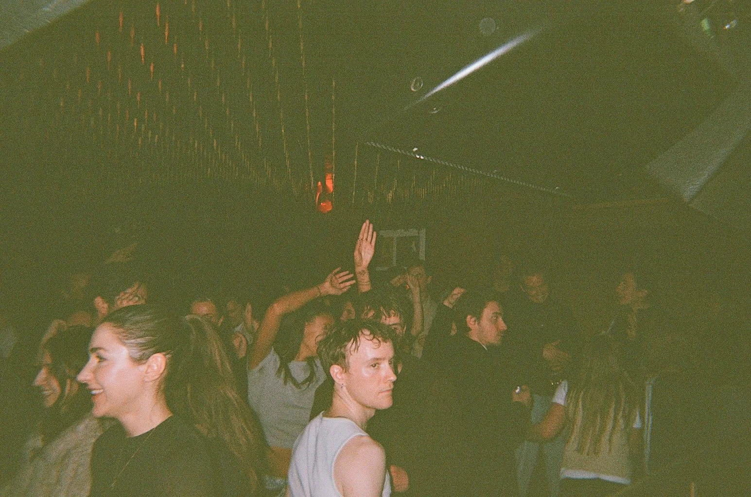 People dancing and enjoying music at a nightclub with dim lighting and disco ball reflections.