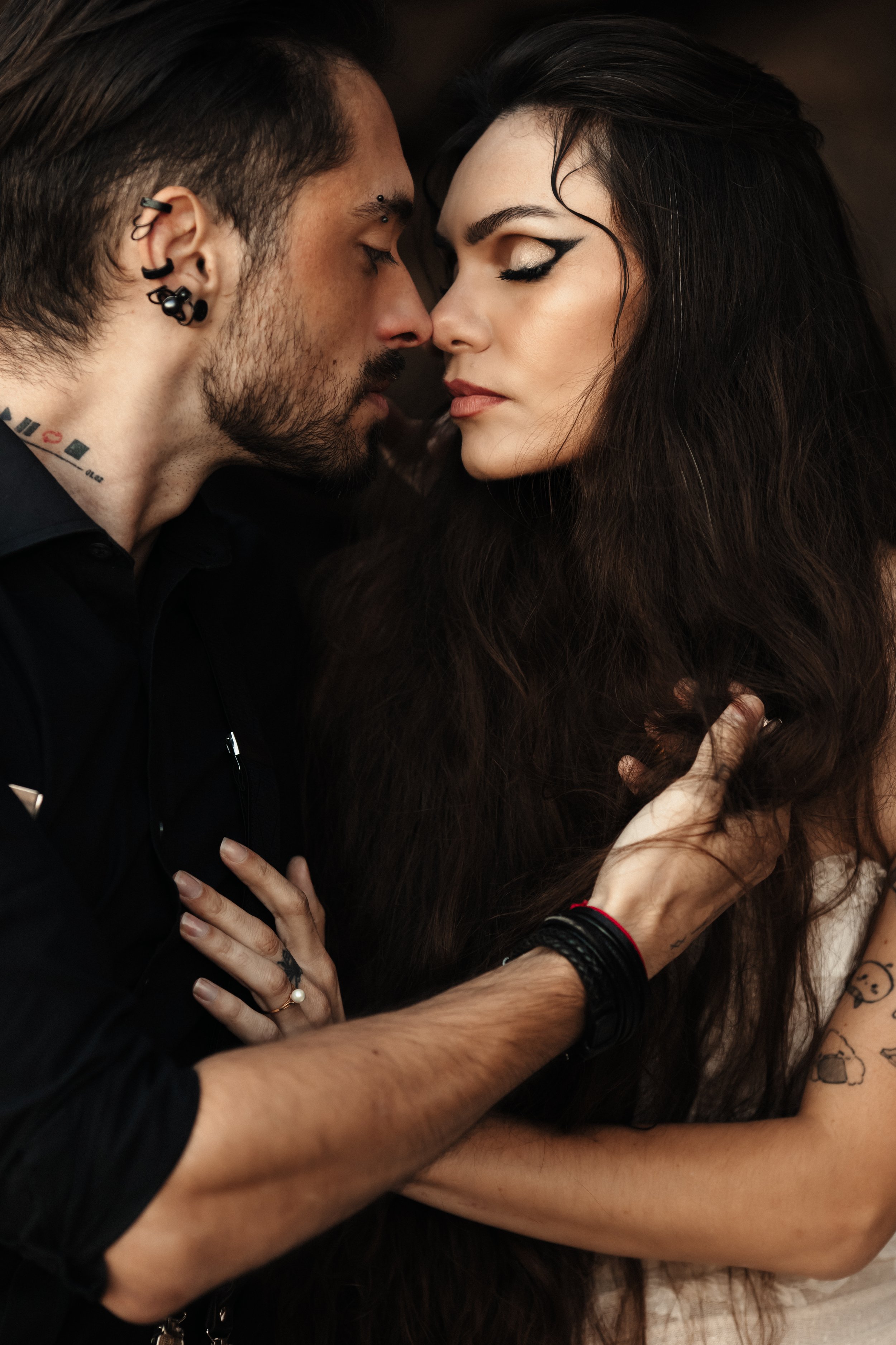 Un homme et une femme se touchent le visage et se regardent avec intensité, dans une ambiance intime.