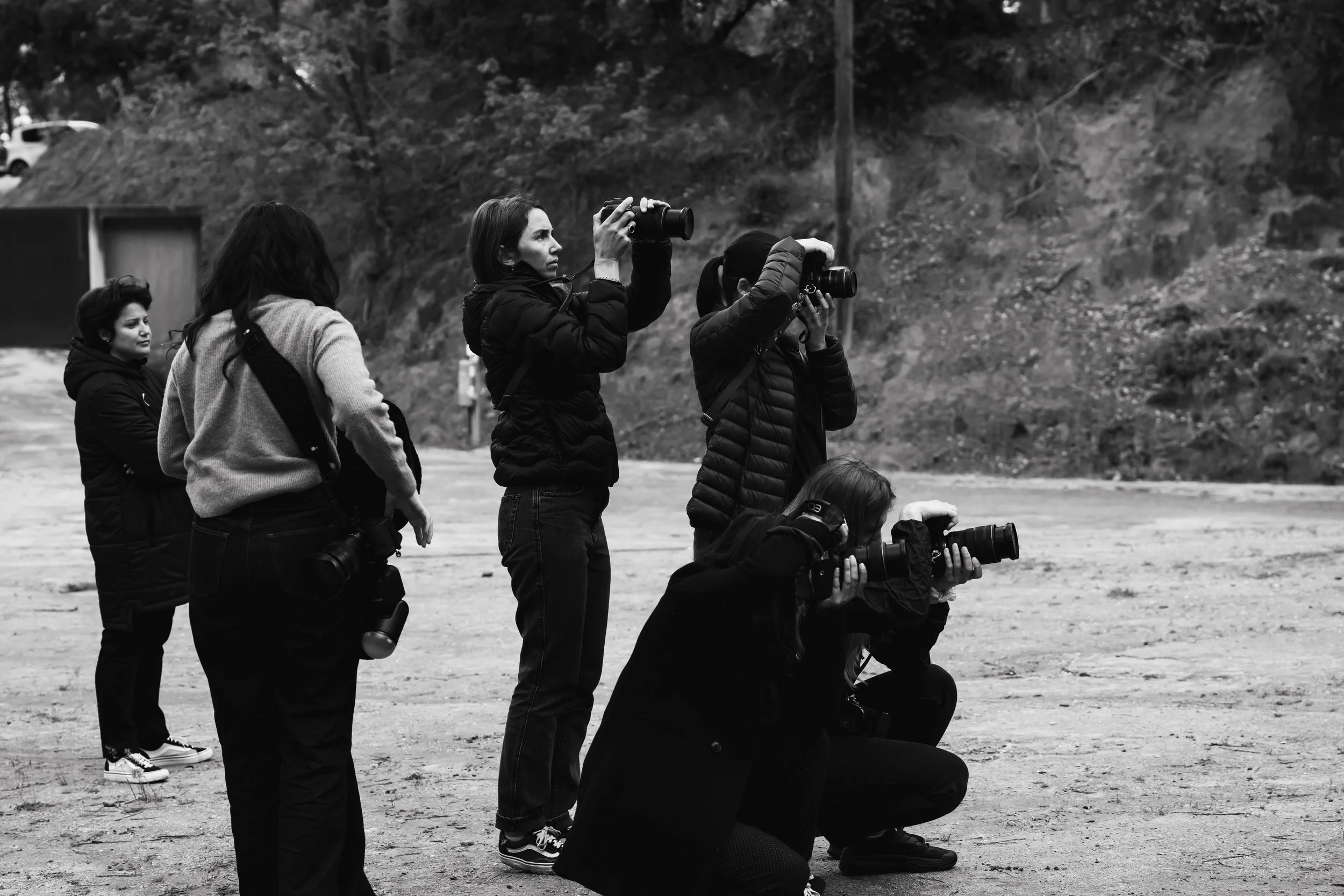 Groupe de cinq photographes prenant des photos en extérieur dans un environnement naturel.