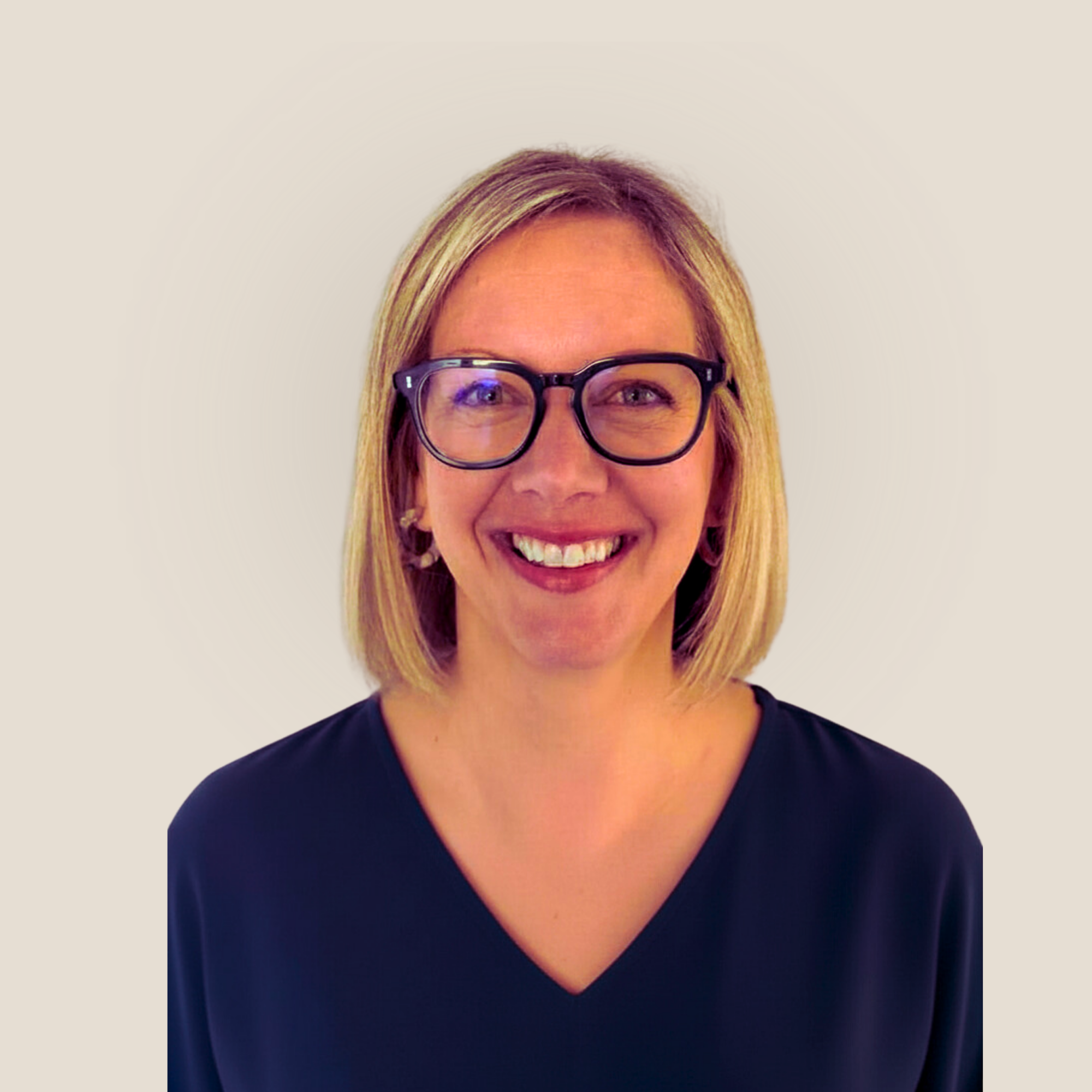 A woman with blonde hair, wearing glasses and gold earrings, smiling at the camera against a white background. Her name is Lucy Williams