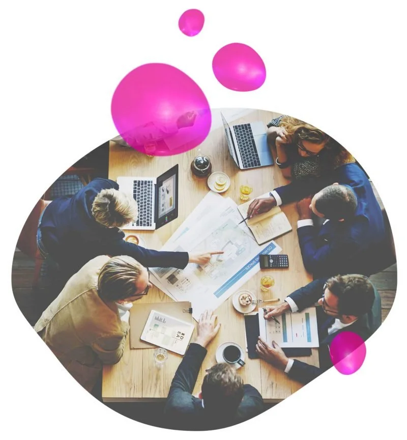 Employees talking while sitting around a desk. They are engaging with each other and enjoying connecting while working.