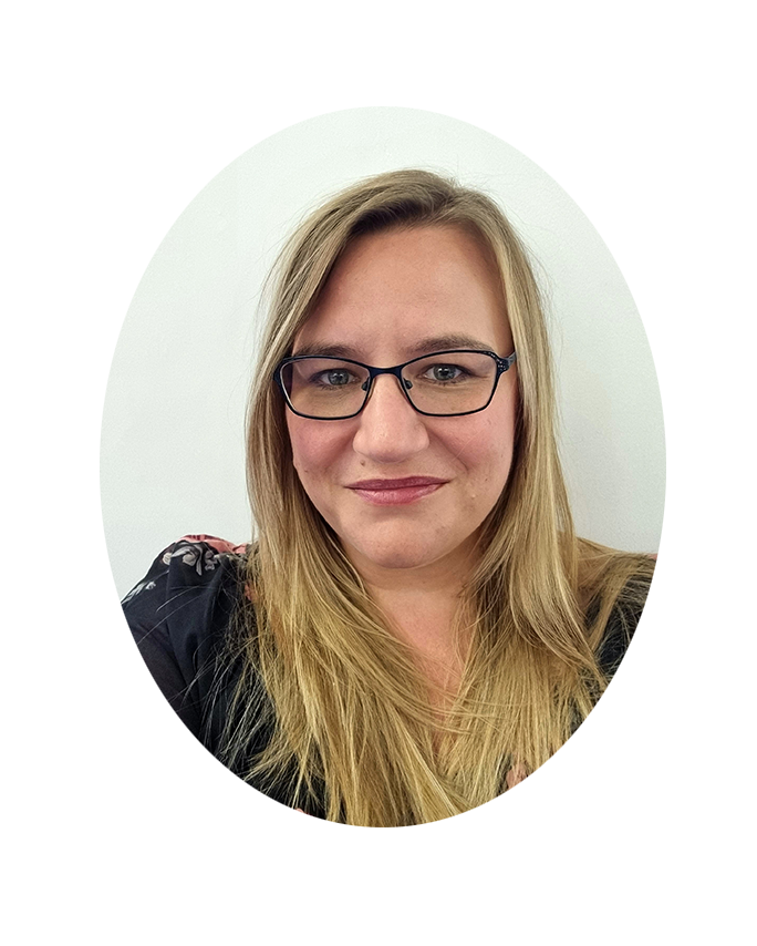 A woman with long blonde hair and glasses smiling at the camera with a plain white background. Her name is Tracey Corney 