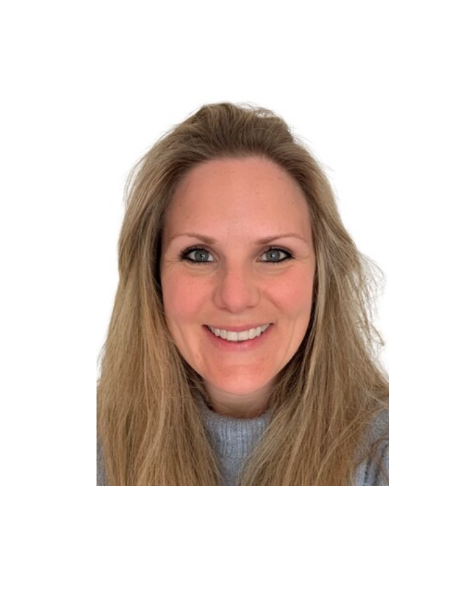 Close-up of a smiling woman with long blonde hair, blue eyes, and wearing a gray sweater against a white background. Her name is Lucie Kern