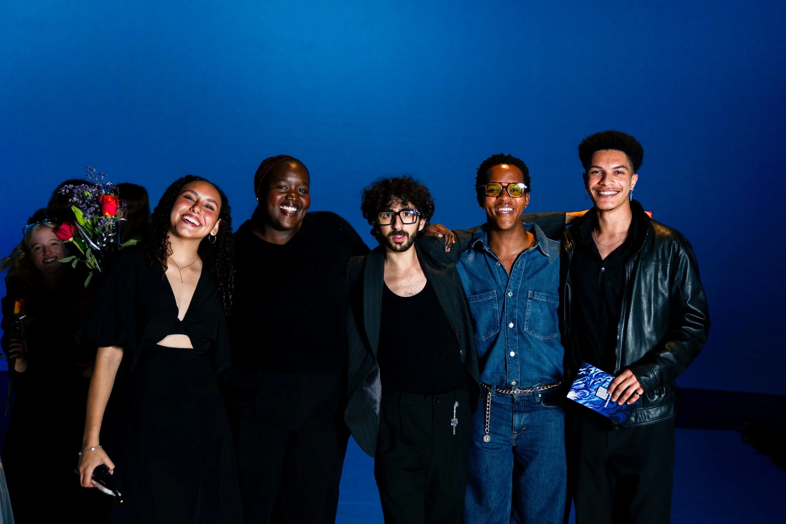 Group of six diverse smiling people standing together against a blue background
