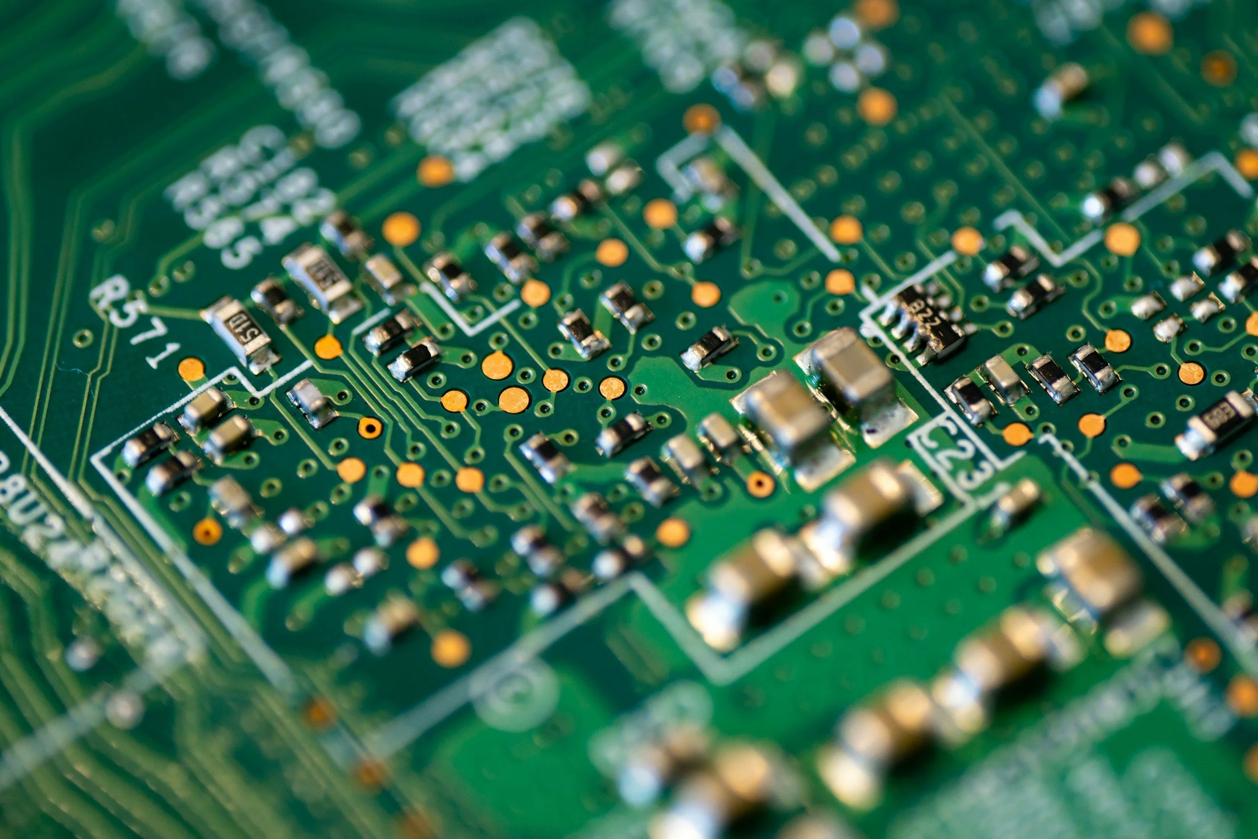 Close-up of a green printed circuit board with various small electronic components and copper traces.