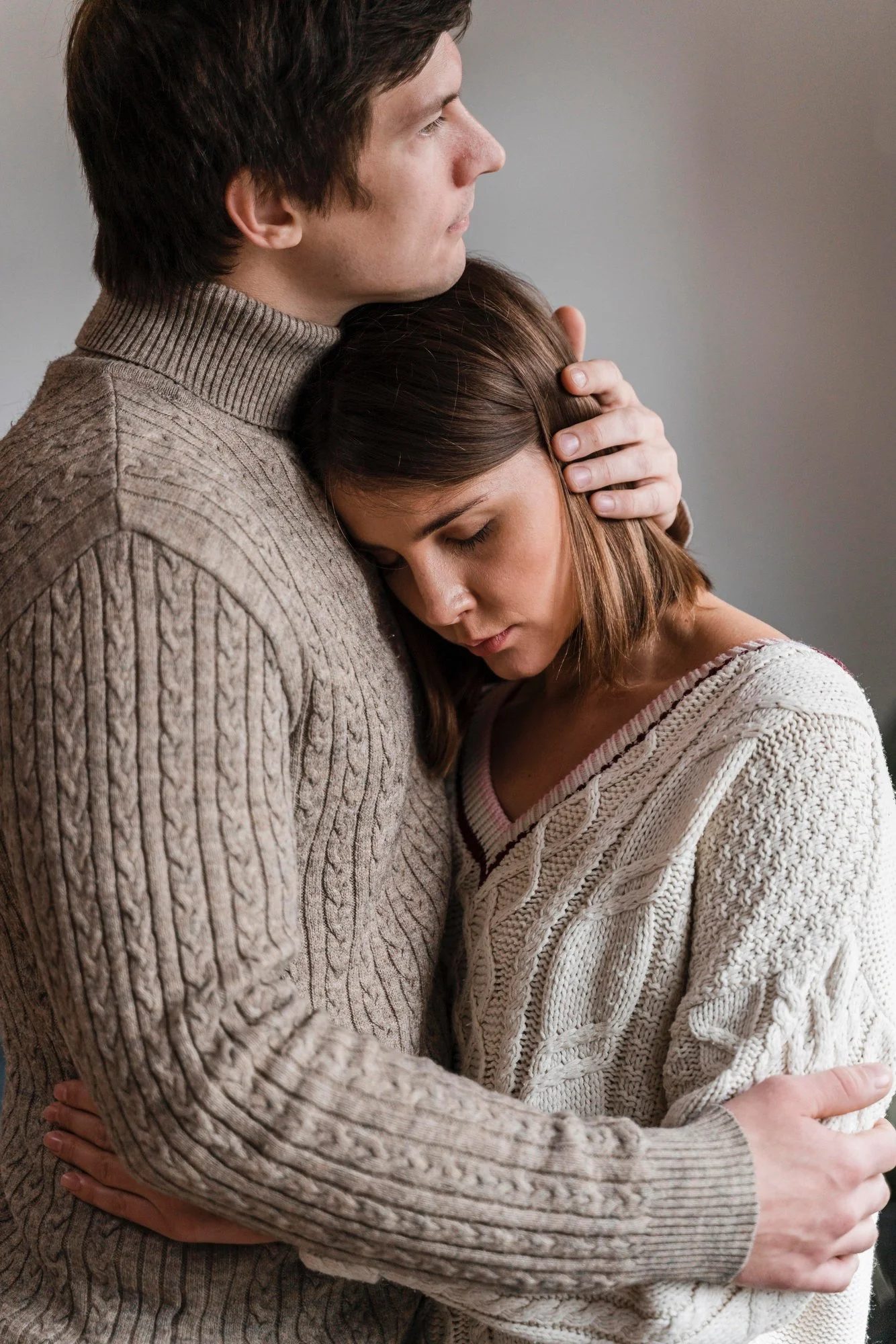 Young man tenderly holding a woman as she rests her head against his chest, representing Universal Human Foundation's support for emotional connection, compassion, and healthy relationships.