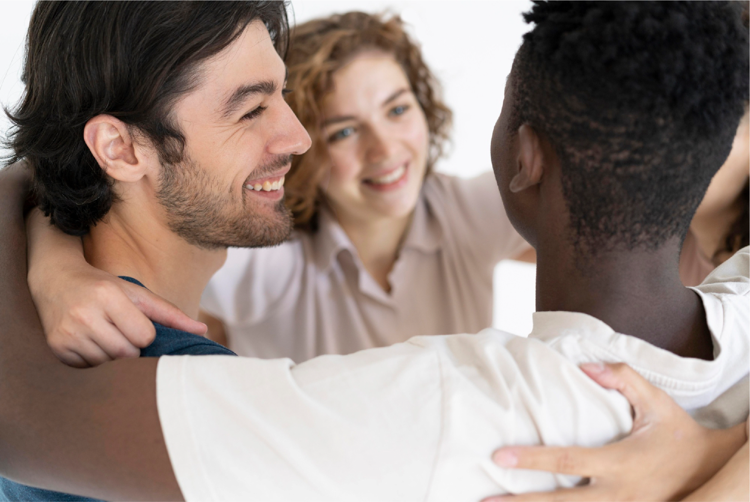 Three diverse young friends sharing a warm, joyful embrace and laughter, representing Universal Human Foundation's support for authentic connection, belonging, and community.