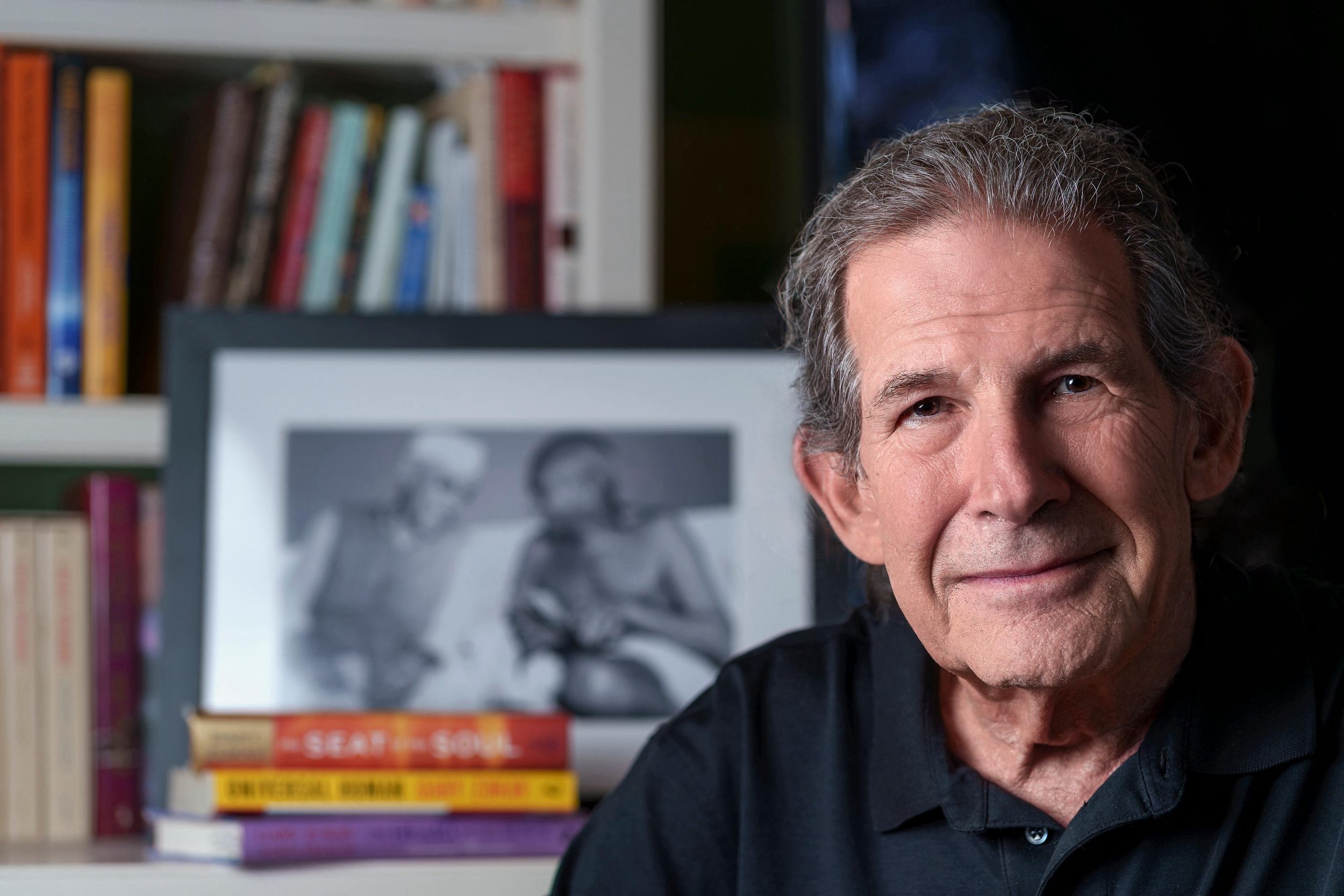 Gary Zukav portrait in a thoughtful indoor setting with books in the background, reflecting wisdom, emotional awareness, and a lifetime of spiritual teaching