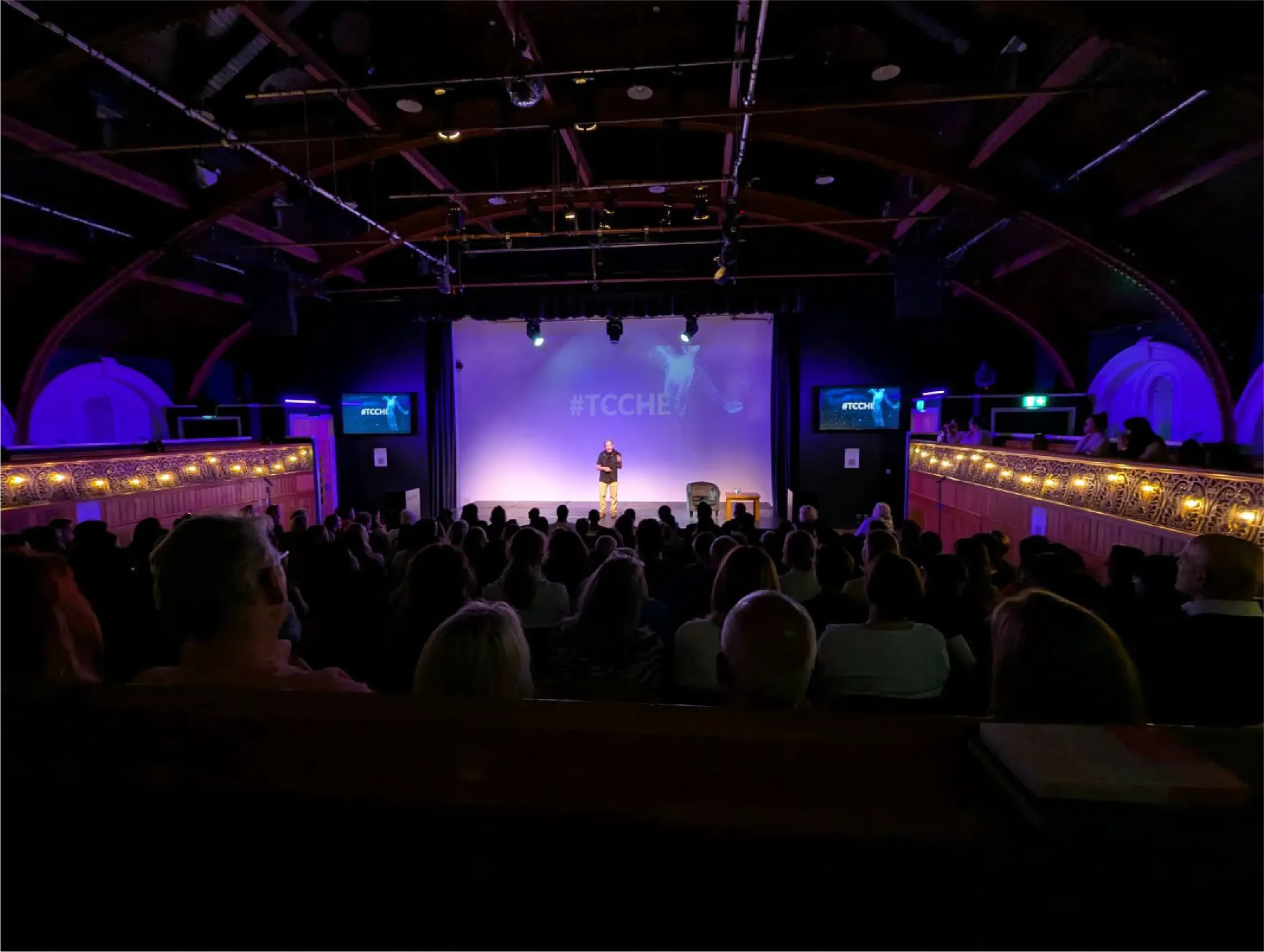 Gary Zukav on stage addressing a full auditorium audience at a live event, sharing teachings in a community gathering supported by Universal Human Foundation.