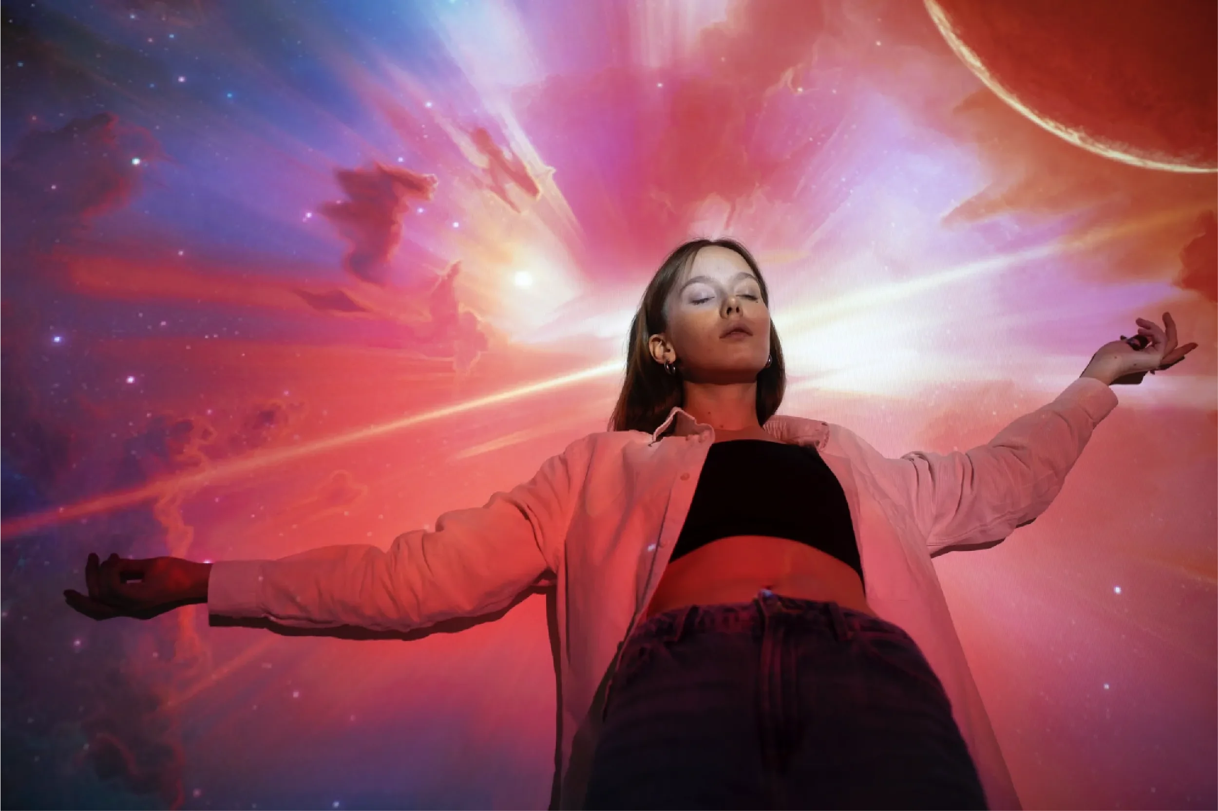 Young woman with arms outstretched and eyes closed against a vibrant cosmic sky with stars and nebulae, representing Universal Human Foundation's support for spiritual awakening, consciousness expansion, and inner transformation.