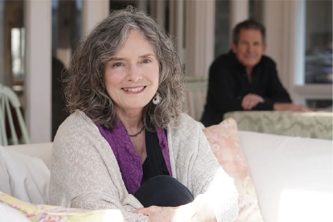 Linda Francis, co-founder of Seat of the Soul Institute, smiling warmly in a cozy home setting with Gary Zukav in the background.