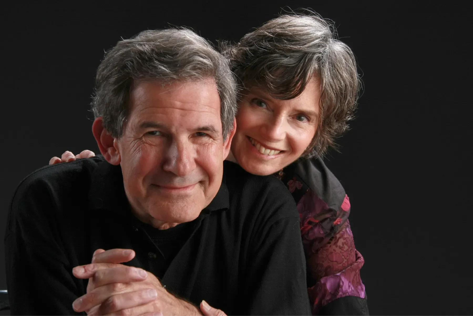 Portrait of Gary Zukav and Linda Francis, co-founders of Seat of the Soul Institute, smiling together against a dark background.