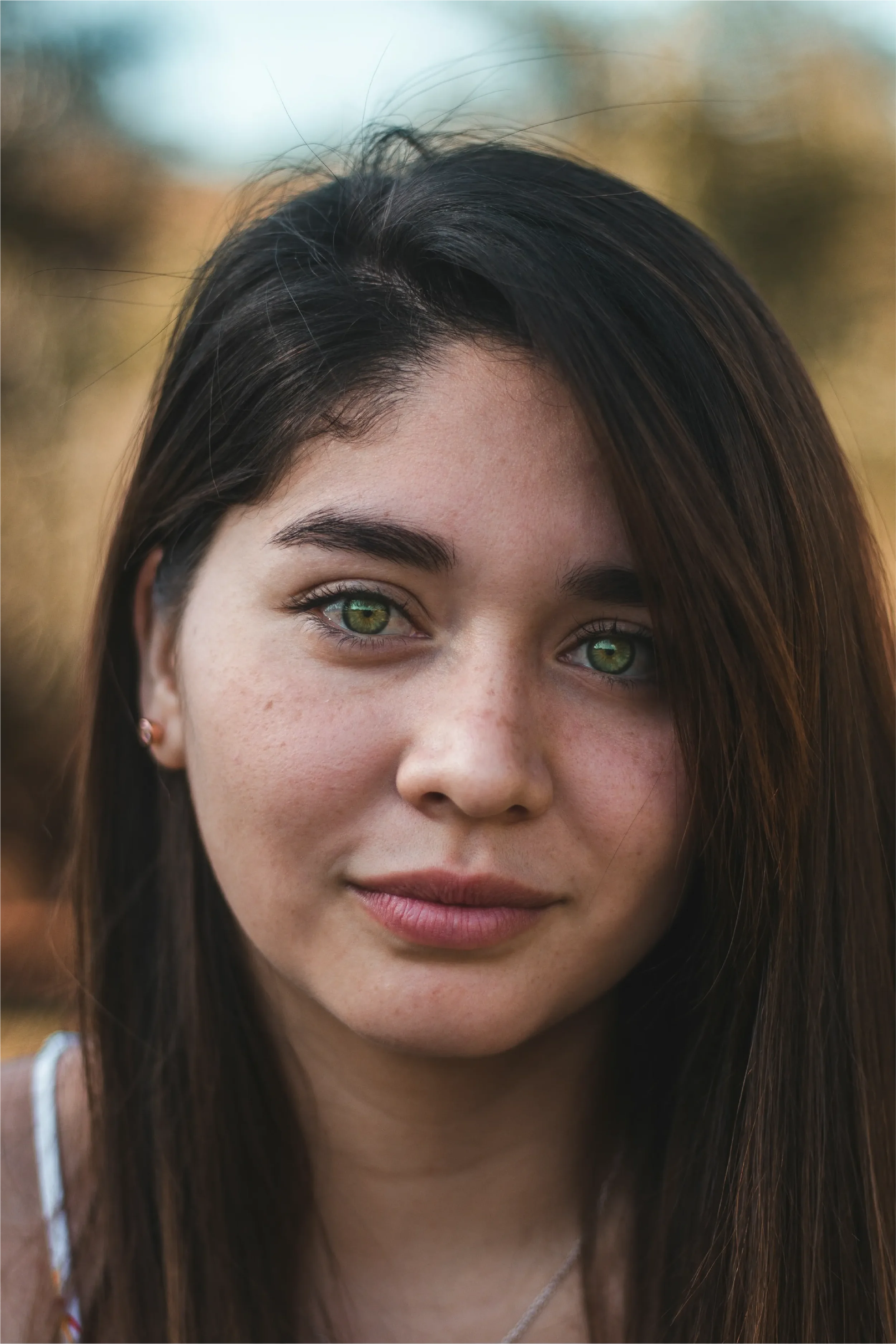 Close-up portrait of a young woman with striking green eyes and dark hair gazing directly at the camera, representing Universal Human Foundation's support for authentic self-expression and personal presence.