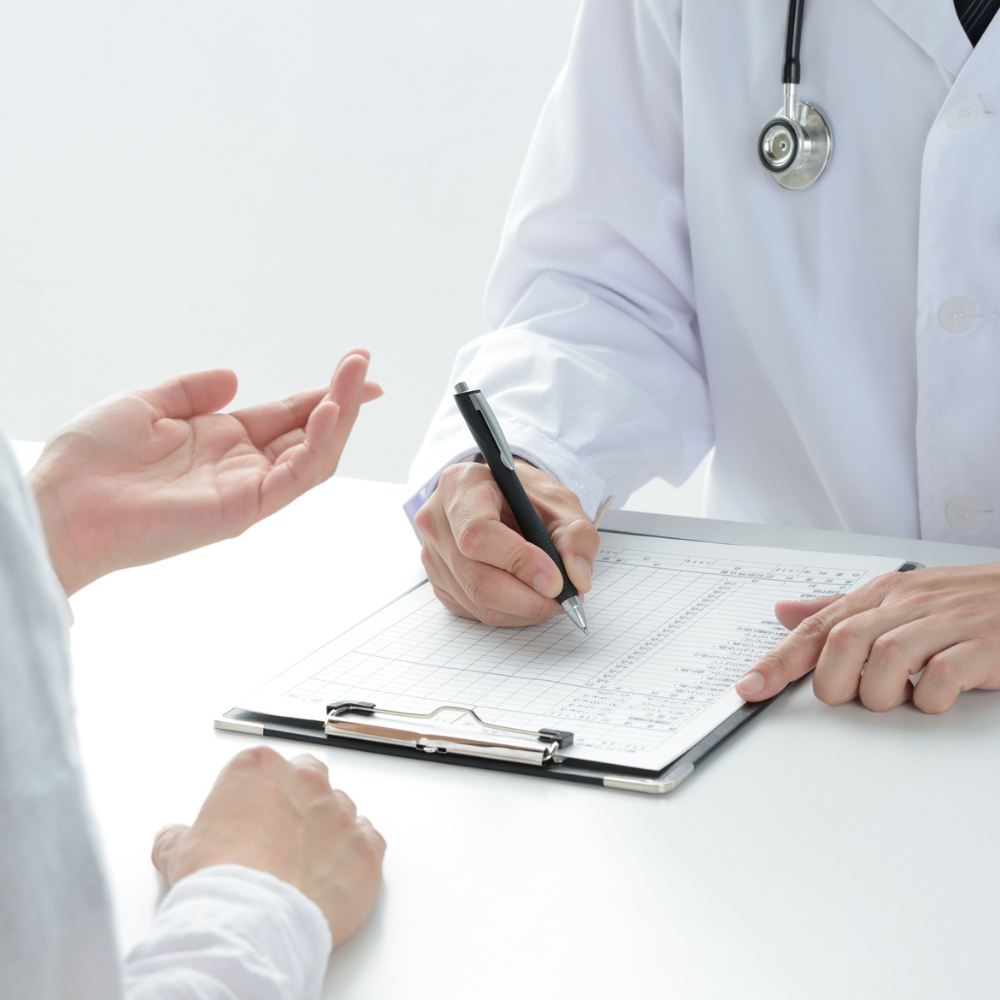 Doctor taking notes on a clipboard during a consultation with a patient.