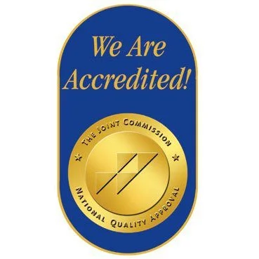 Certificate or badge with an oval shape, blue and gold colors, reading 'We Are Accredited!' and featuring a gold circle with a checkmark and the text 'The Joint Commission National Quality Approval.'