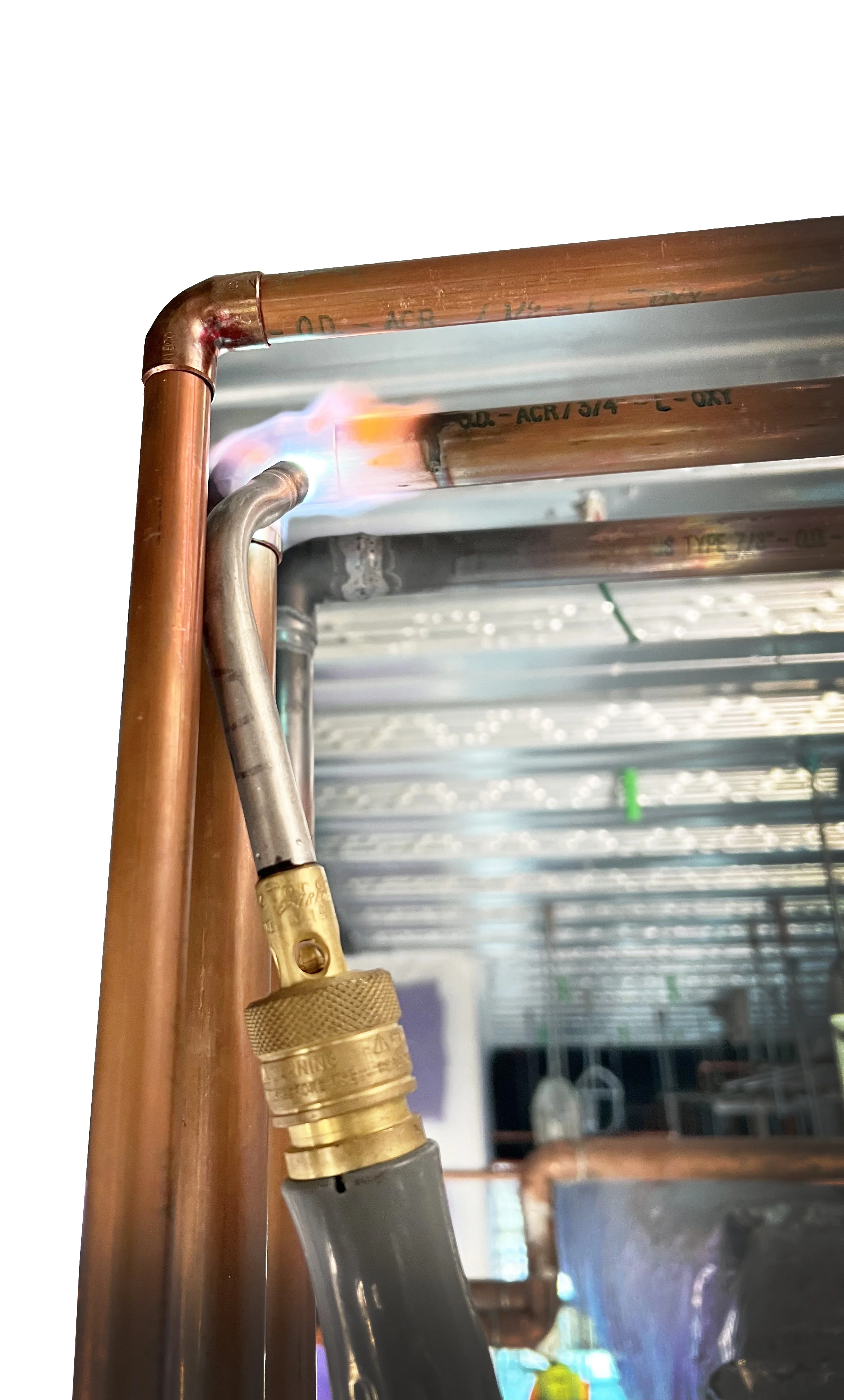 Close-up of copper plumbing with a torch flame heating a pipe joint.