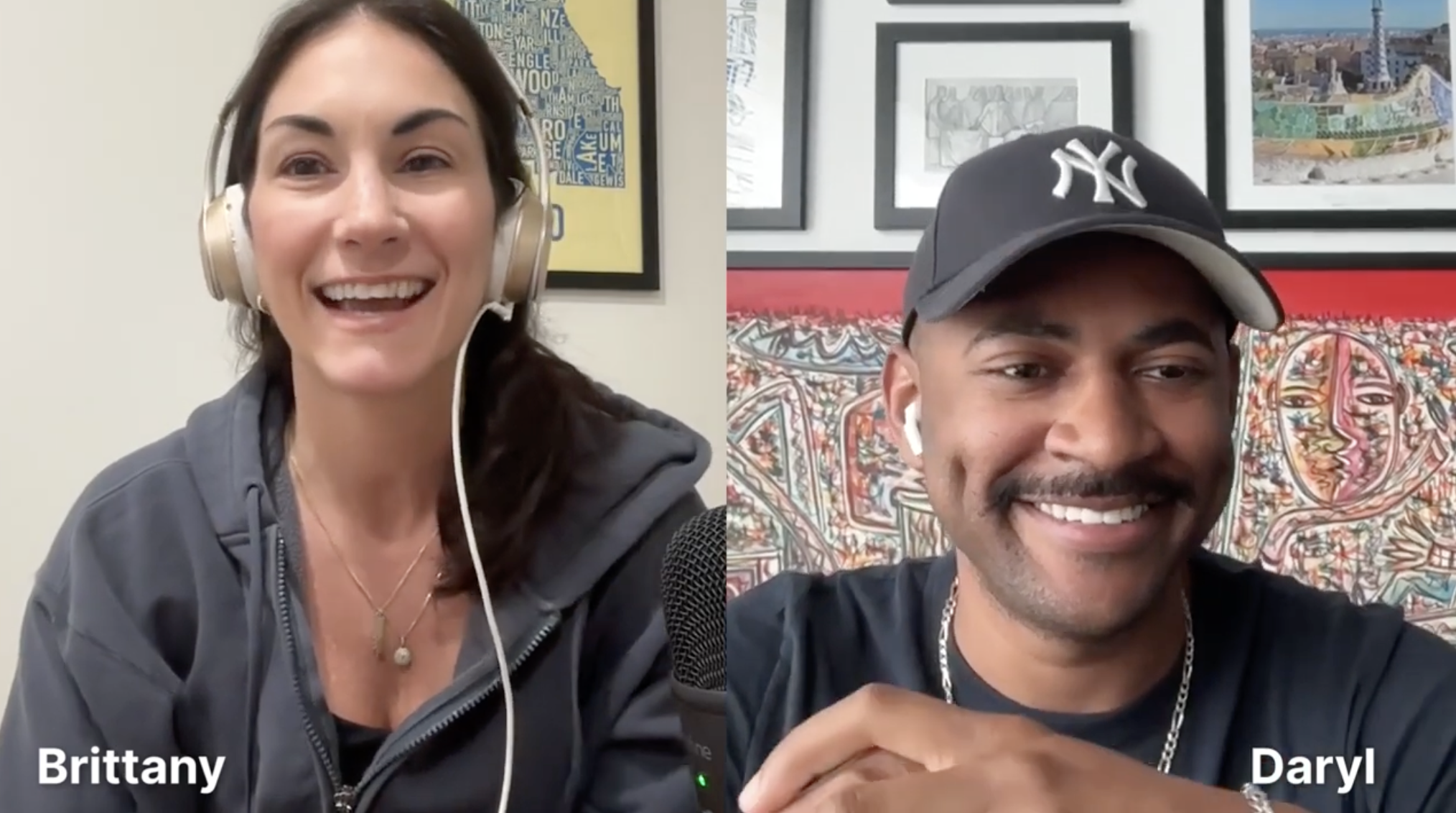 Two people in a video call, a woman named Brittany on the left wearing headphones and a dark zip-up hoodie, and a man named Daryl on the right wearing a black baseball cap with a New York Yankees logo, a black T-shirt, and smiling, with a background of framed artwork.