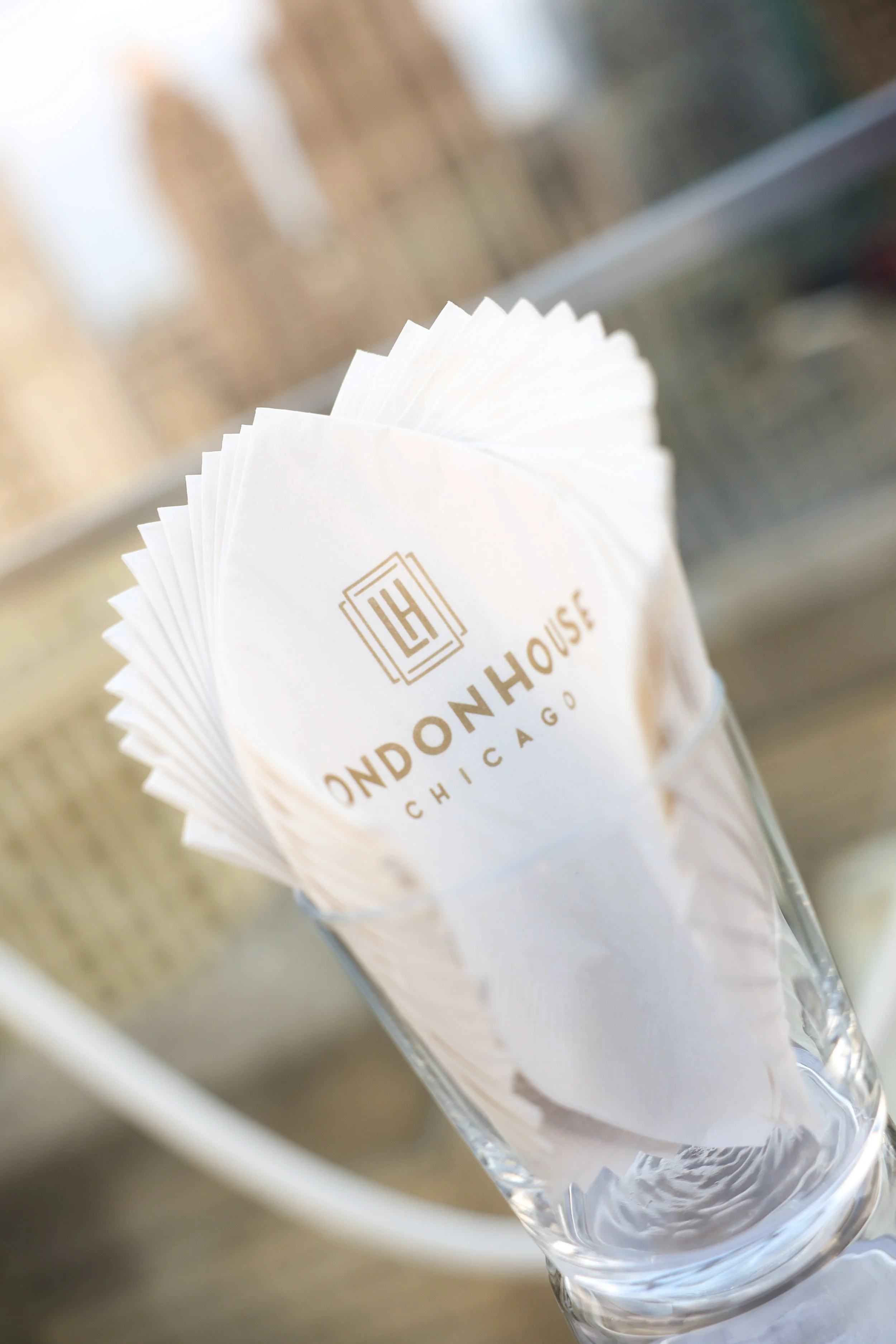 Paper napkins in a glass holder with the logo and text "LONDON HOUSE CHICAGO" printed on one napkin.